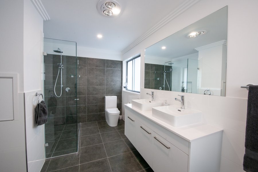 Bathroom with dark grey tiles in shower and white double vanity_Carnelian Projects.jpg