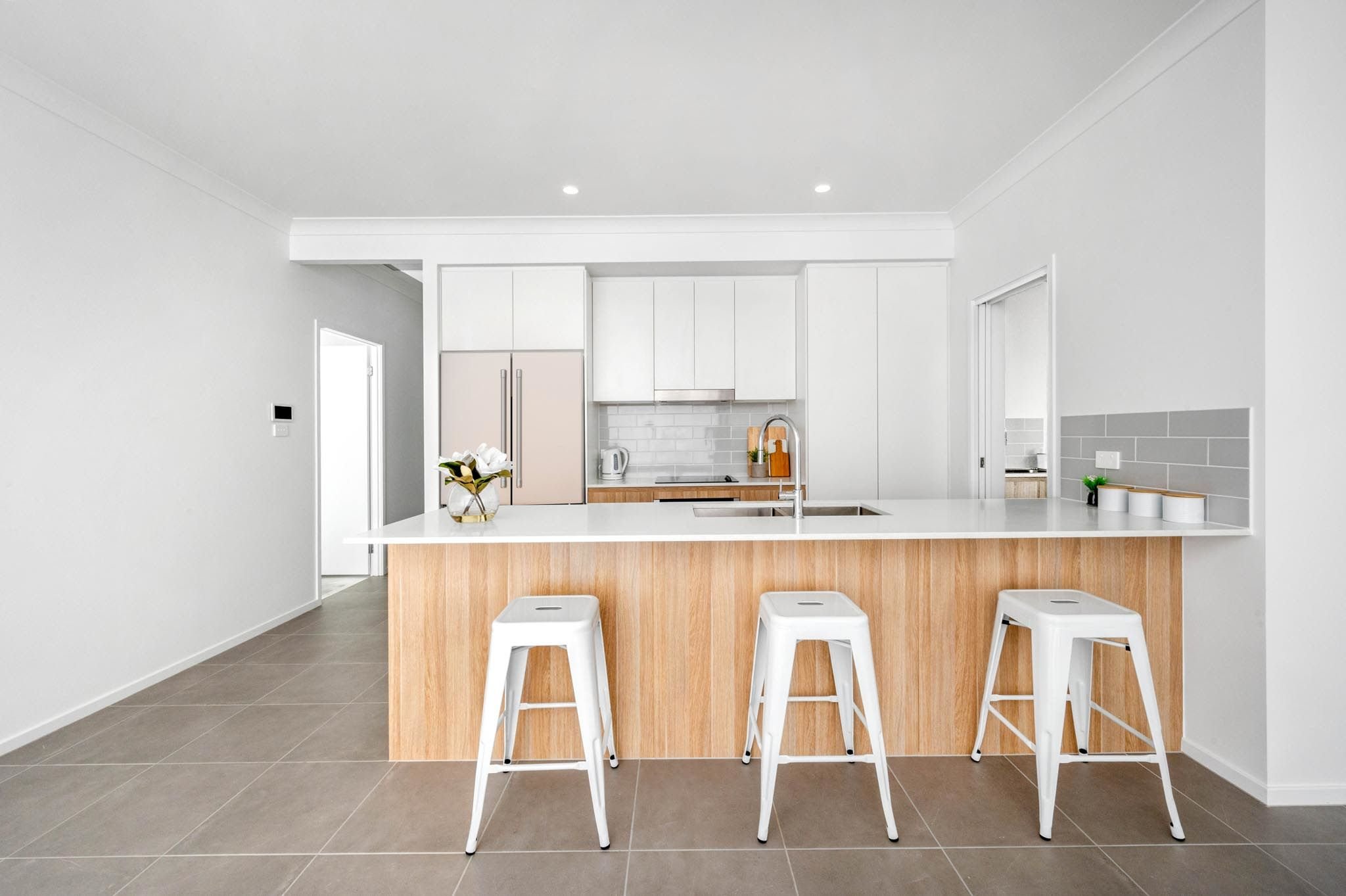 White kitchen with light oak wooden cabinetry, grey floor tiles, grey subway tiles splashback, chrome gooseneck tap and white stools_Carnelian Projects.jpg