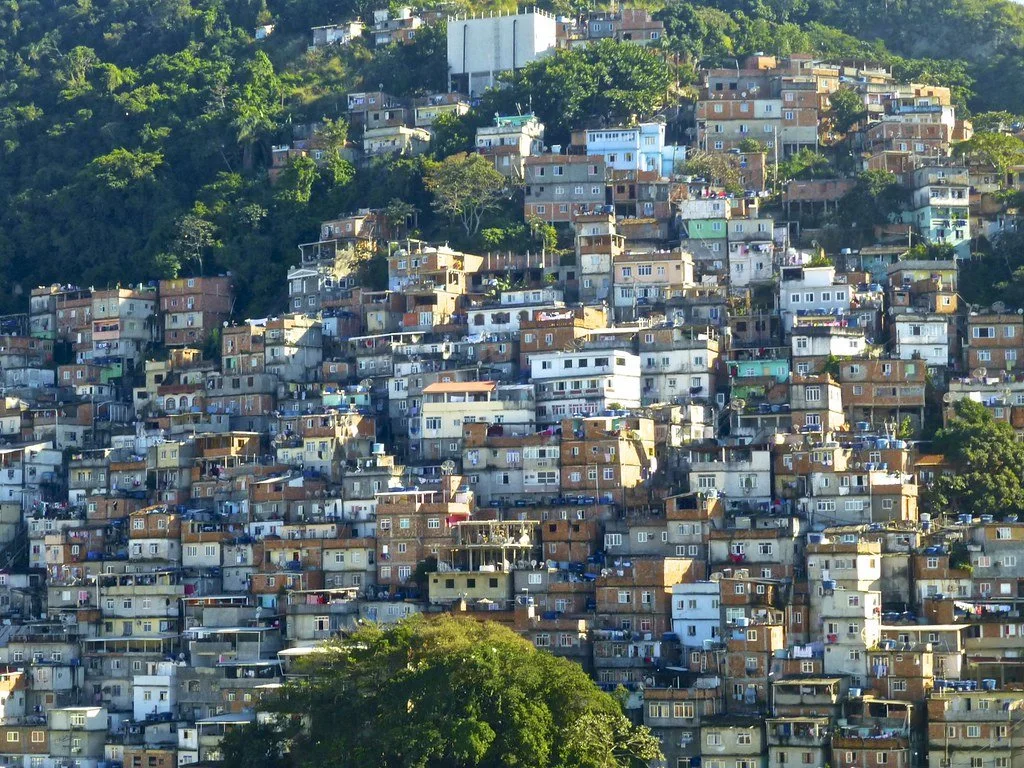 A densely packed hillside neighborhood with numerous small, multi-colored houses stacked closely together.