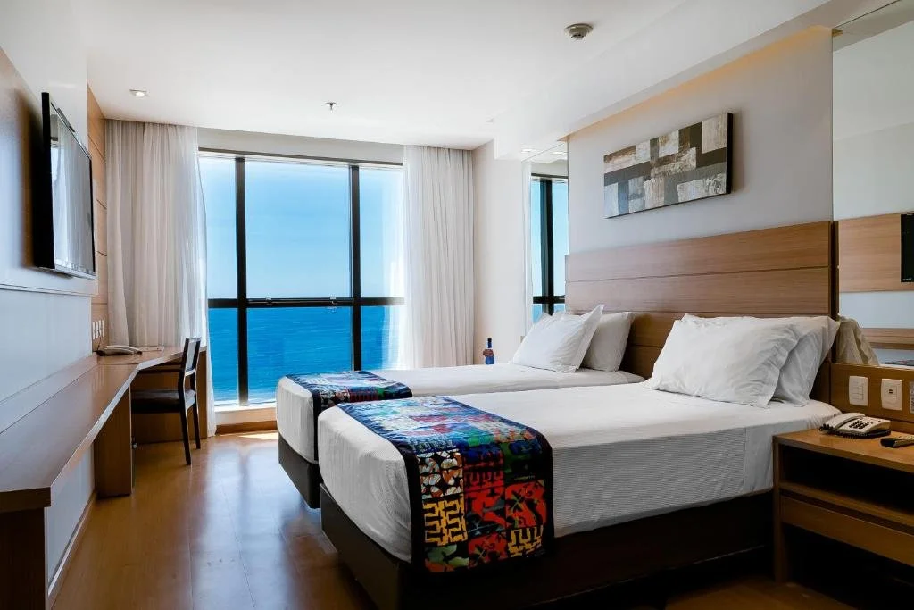 Hotel room with two beds, ocean view, wooden furniture, and modern decor.