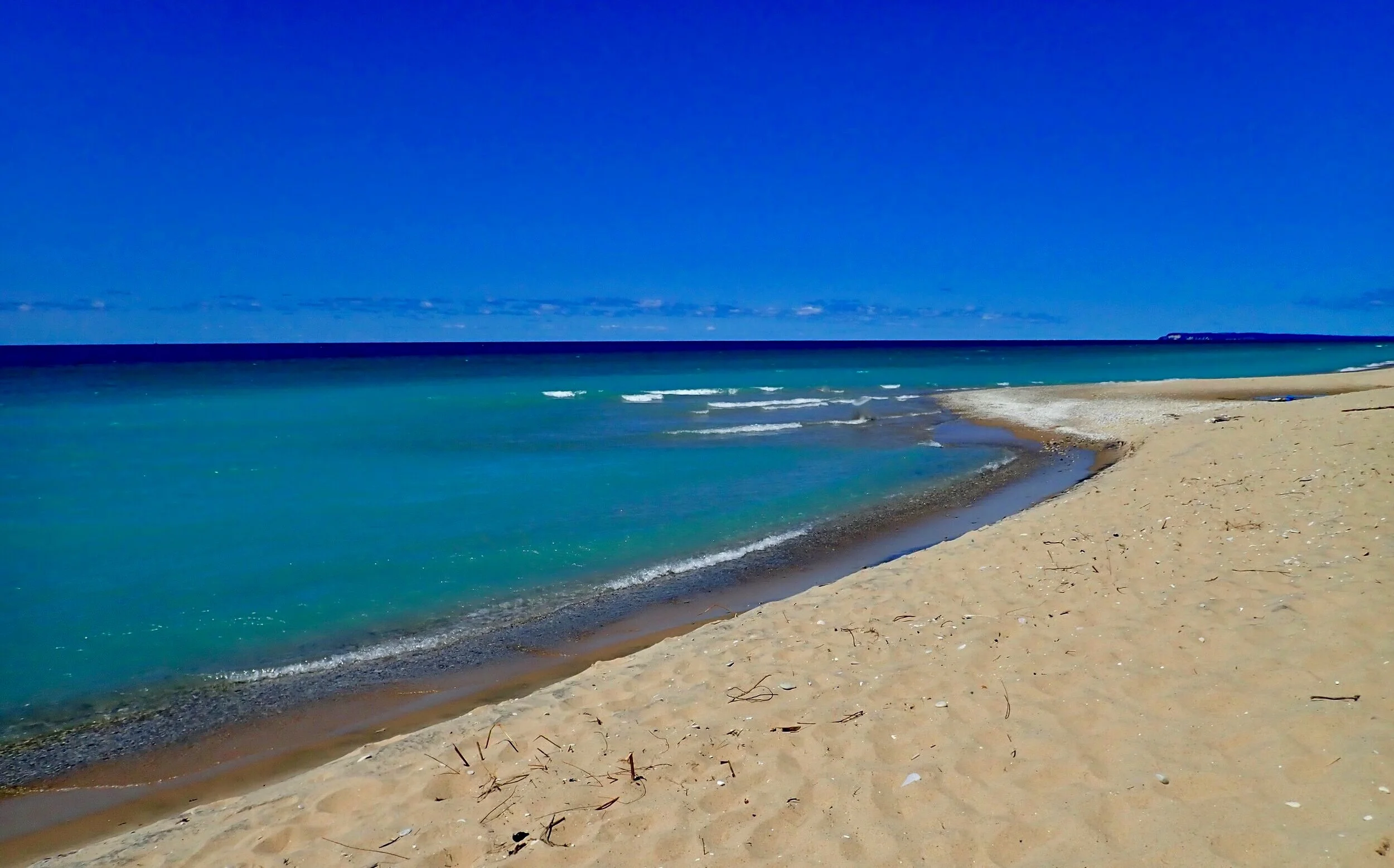 A sandy beach with turquoise water under a clear blue sky.