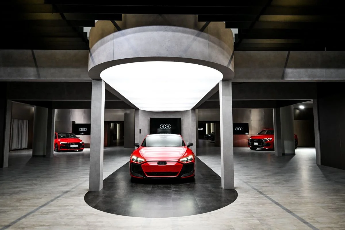 Multiple red Audi cars displayed in a modern, sleek showroom with gray walls and floors.