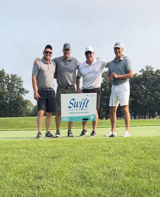 ers pose beside the Swift Printing sponsor sign during the 2026 Walt Gutowski Sr. YMCA Golf Outing.