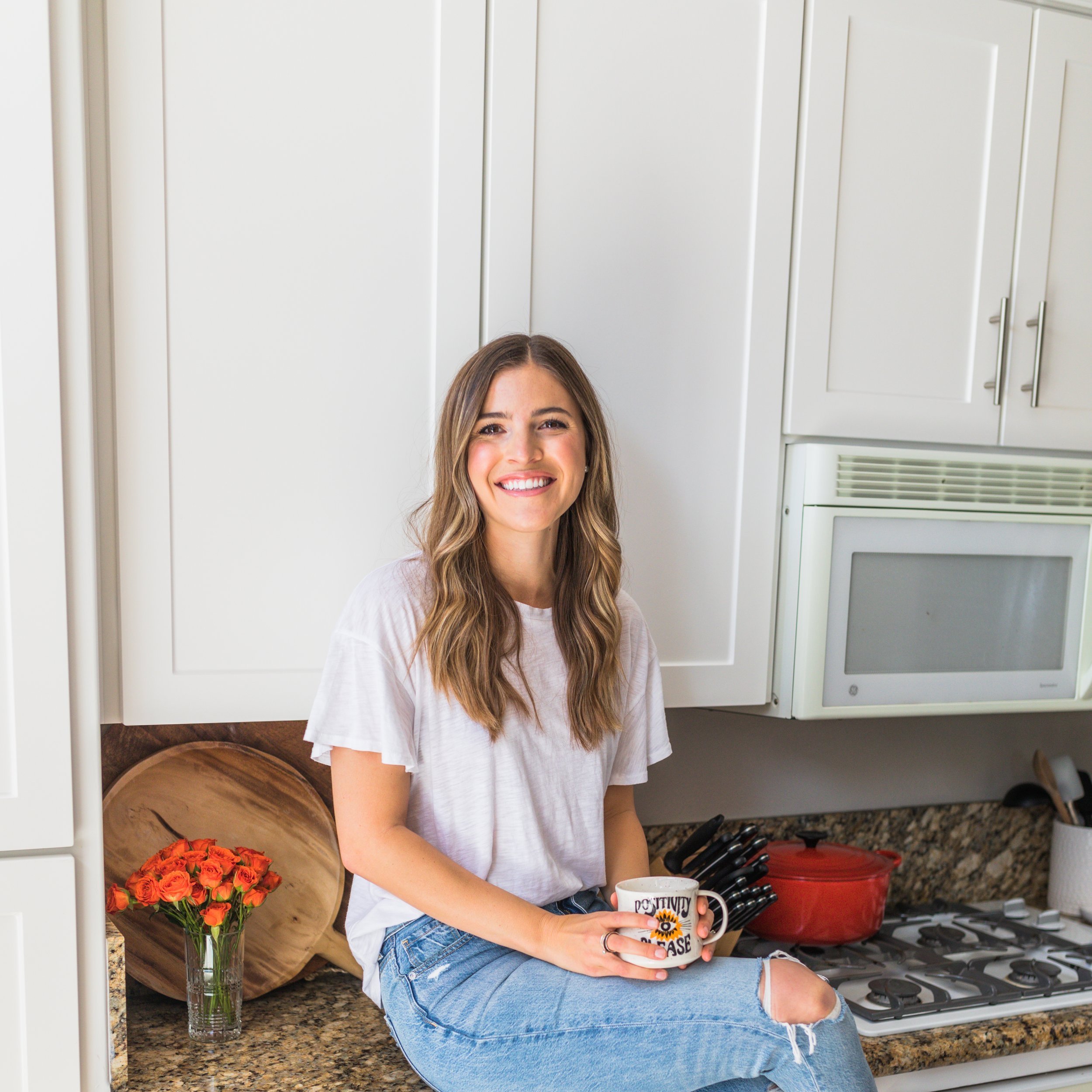 Arielle Pinkston sitting on a counter smiling and holding a mug