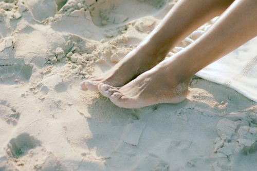 persons feet in the sand at the beach