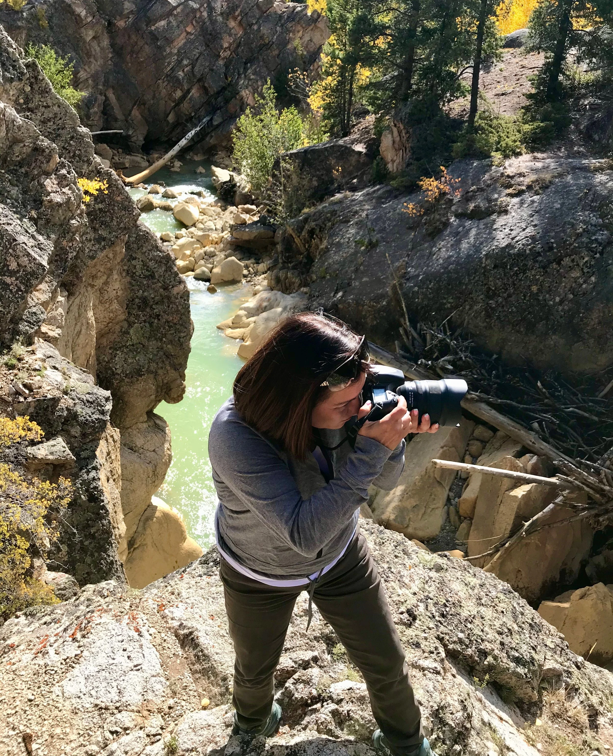 Woman photographing rocky canyon with river