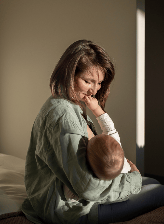A woman sitting on a bed holding a young child in her arms.