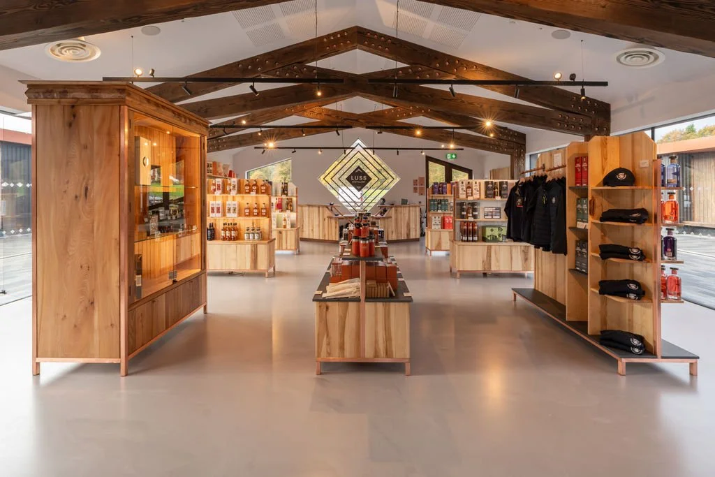 Interior of Luss Distillery with wooden shelves displaying various Gins and whisky.