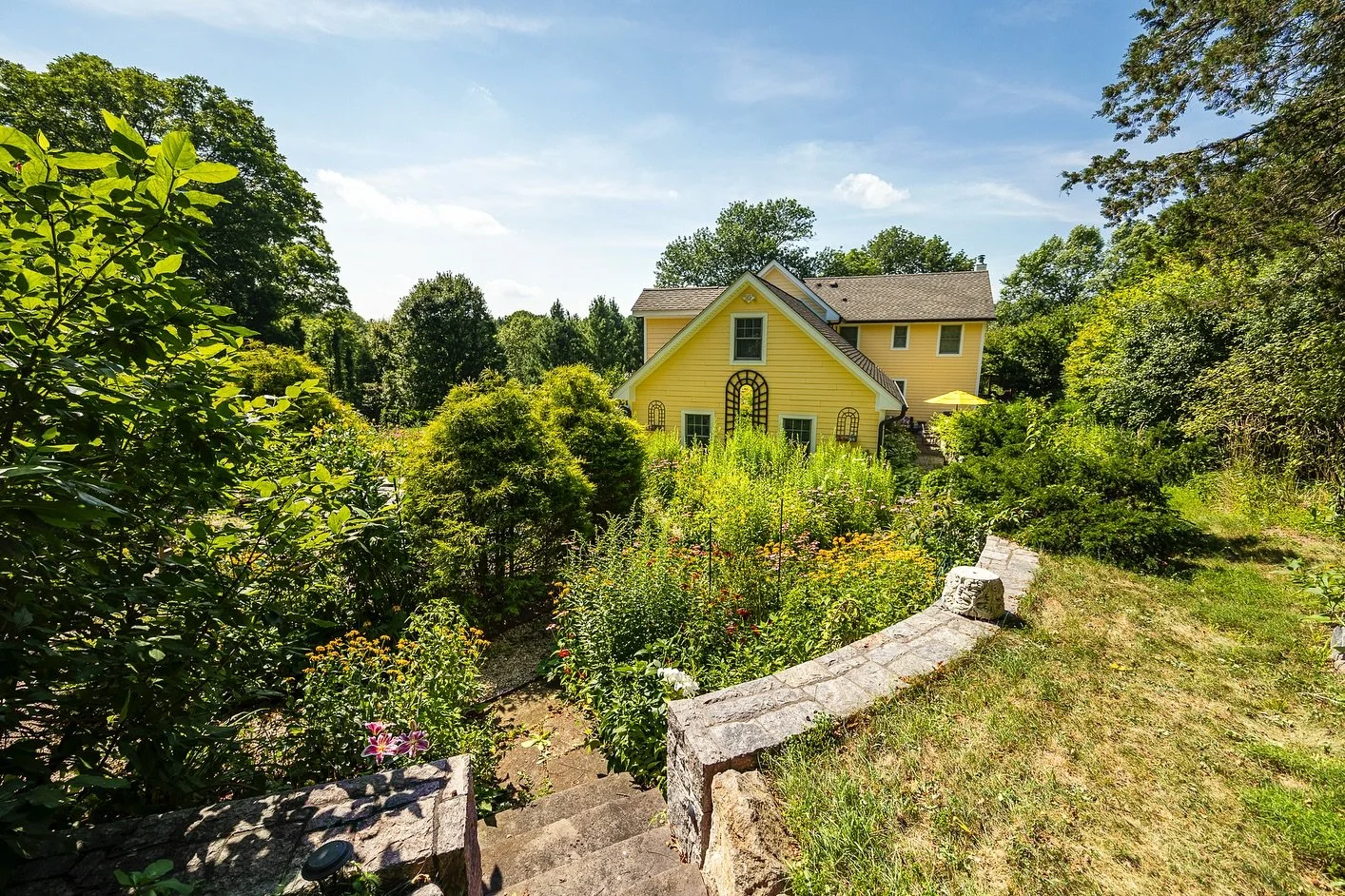 Sunlight, stone walls, and a garden that knows its angles. 
This 1949 Cape Cod, renovated in 2008, sits on 1.25 acres of landscaped beauty with terraces, hidden seating areas, and winding pathways. Outdoors, a pizza oven, Perlick refrigeration, gran