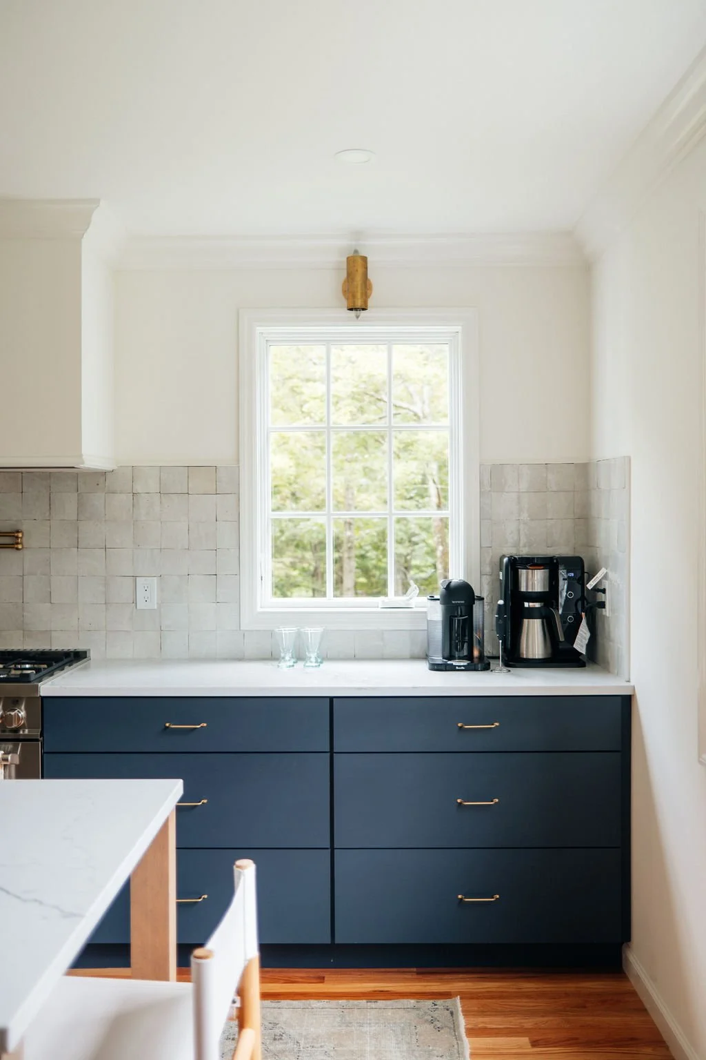 Kitchen counter with blue drawers, coffee maker, and a window showing greenery outside.