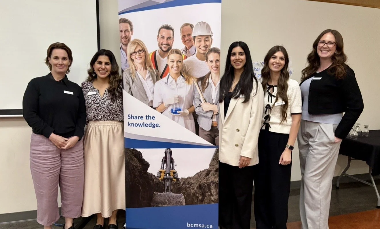 Group of women stand in front of corporate banner