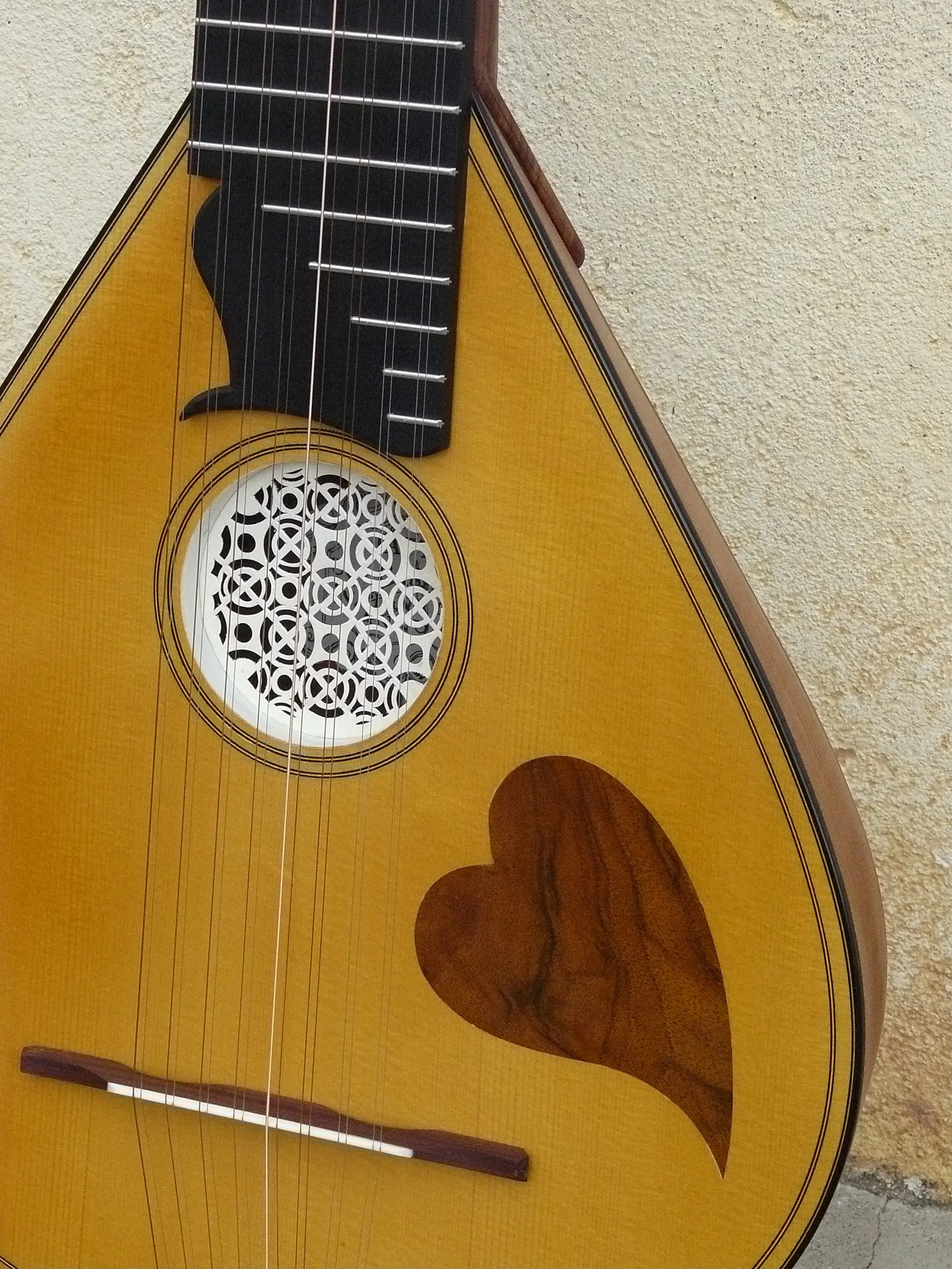 Guitare acoustique avec un corps en bois, un cœur en bois dans la forme d'un cœur, une rosace décorative et un manche noir.