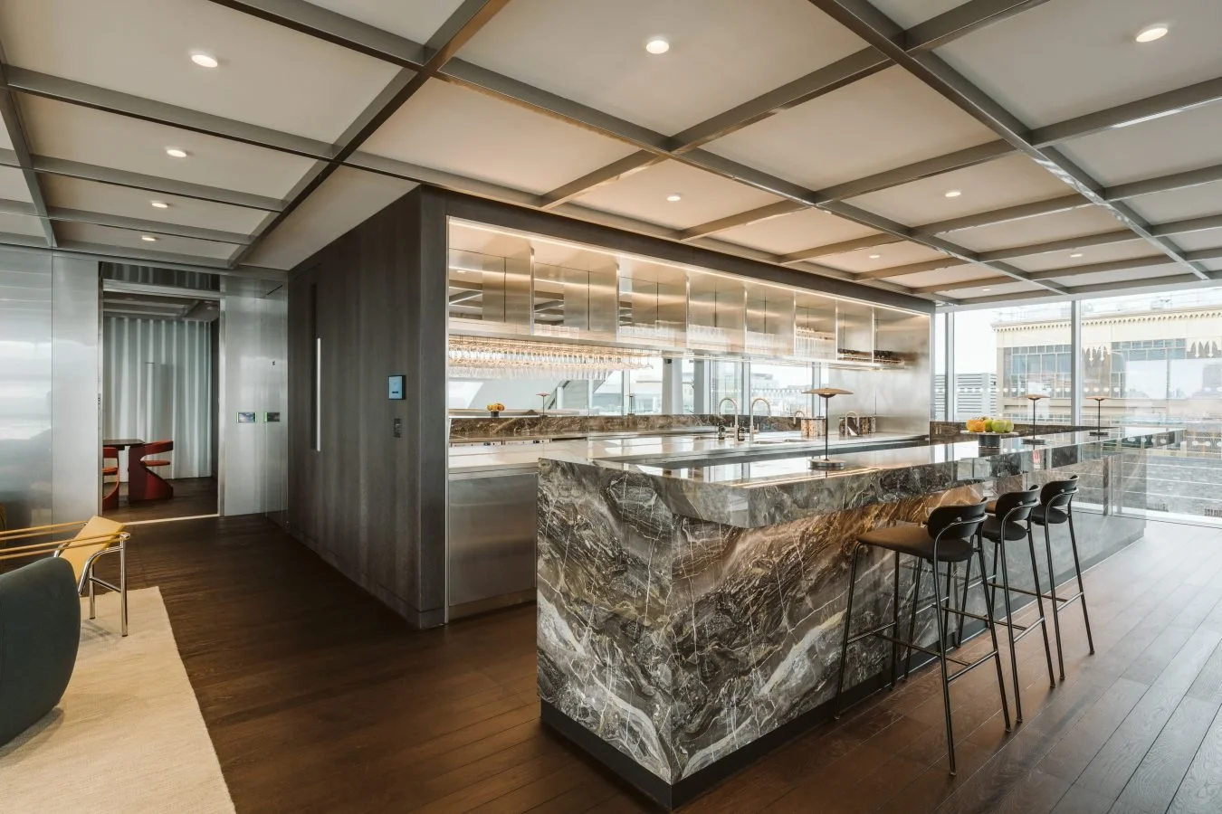 Modern kitchen with marble island, bar stools, and large windows with city views