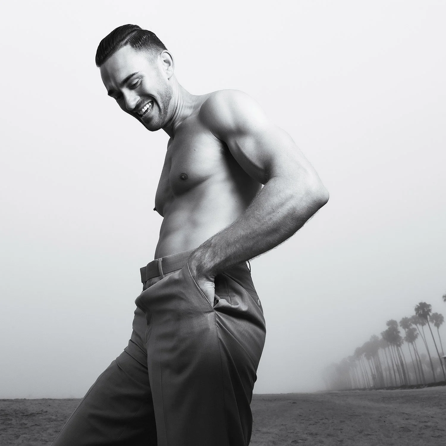 Shirtless male model smiling with his hands in his pockets of  his slacks