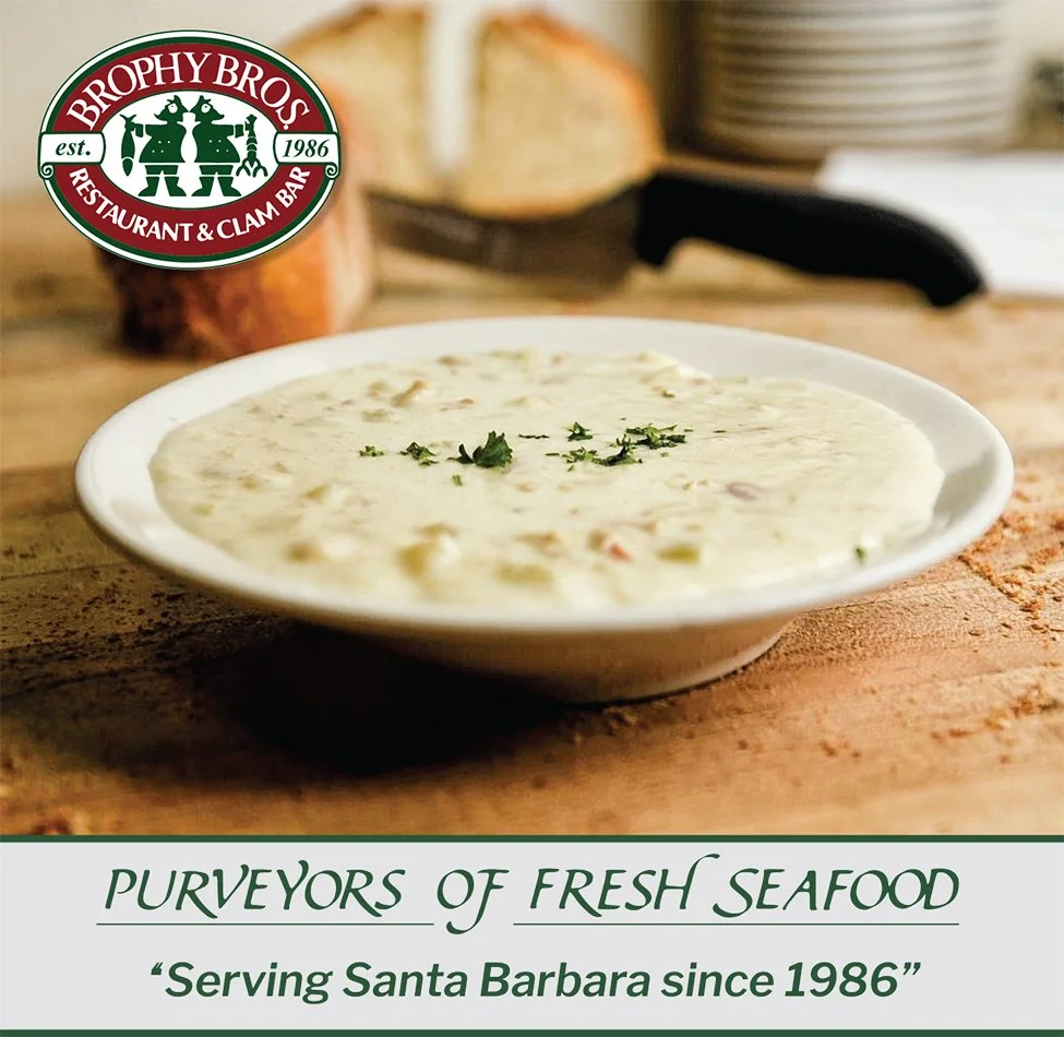 Hot clam chowder in a bowl with fresh bread sliced in background