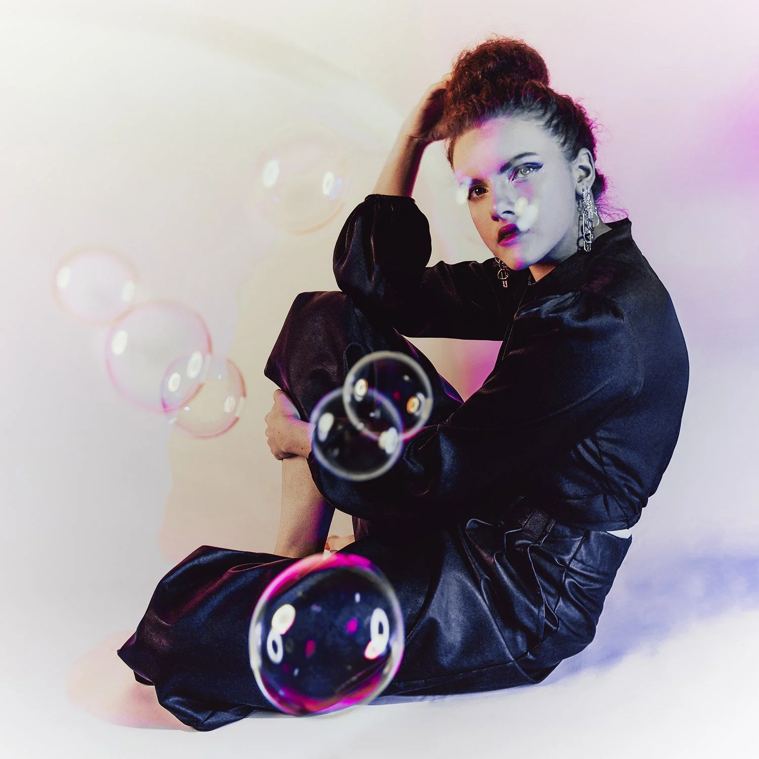 woman gazes through bubbles wearing designer outfit