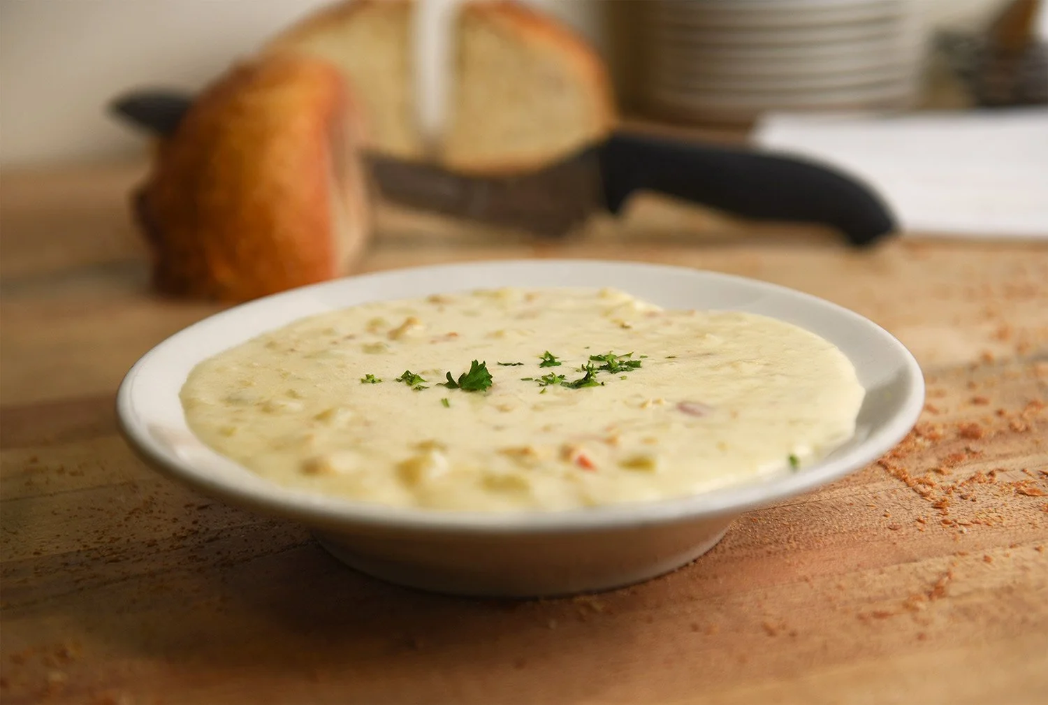 sliced bread sits behind a bowl of hot clam choweder
