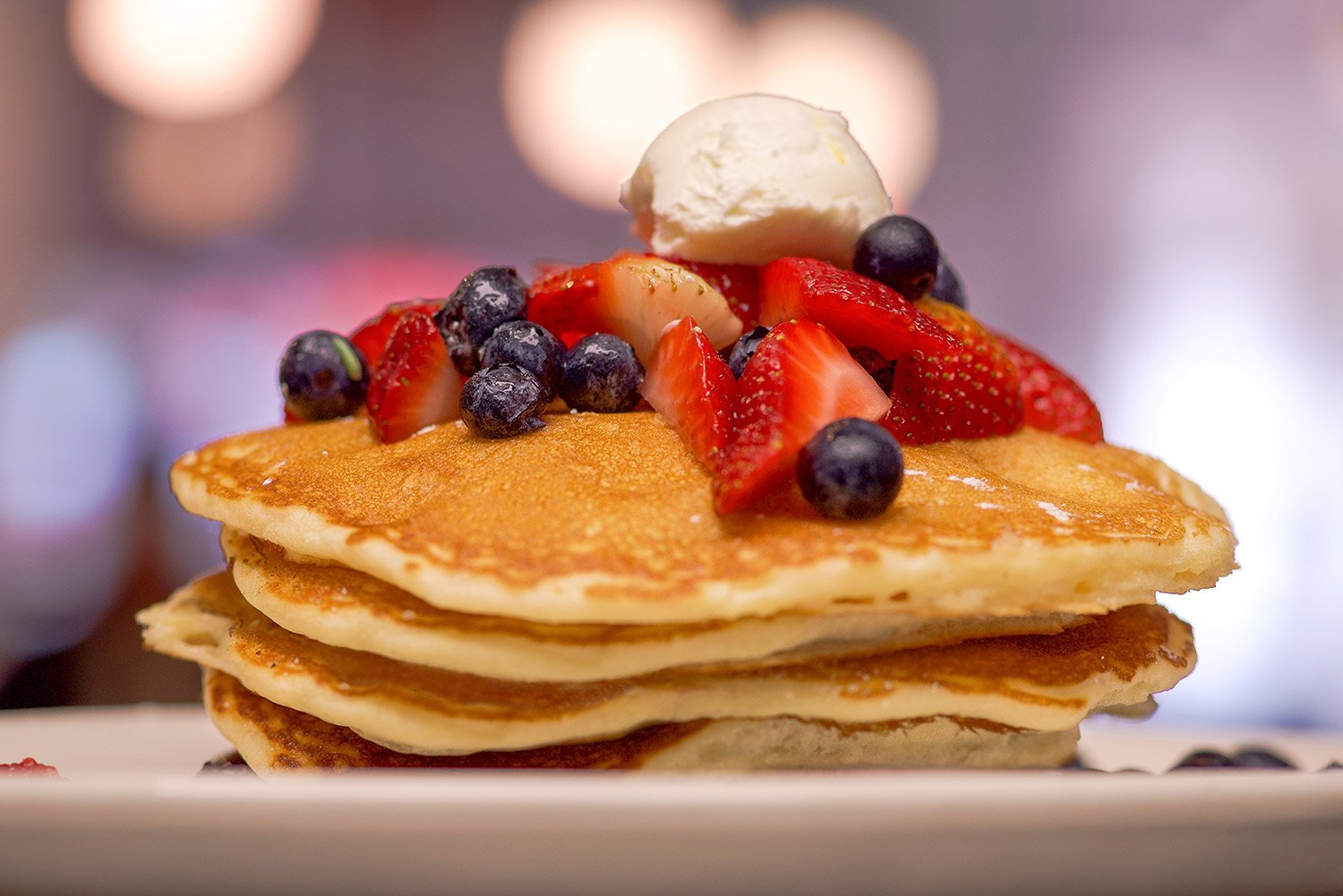 a hot stack of cakes covered in fresh fruit at a diner
