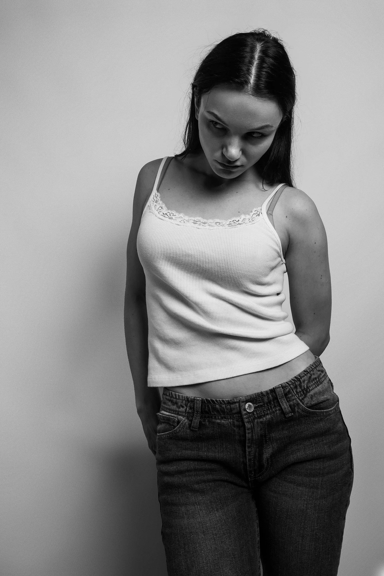 female fashion model wearing jeans and white tank top gazes off to her side