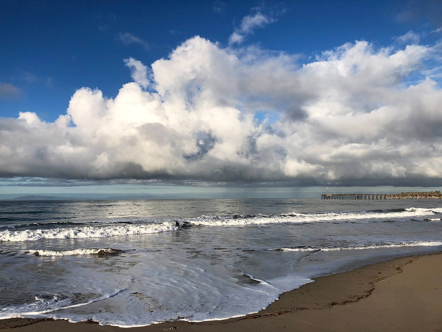 Color photo of large white clouds over the beach in Ventura California
