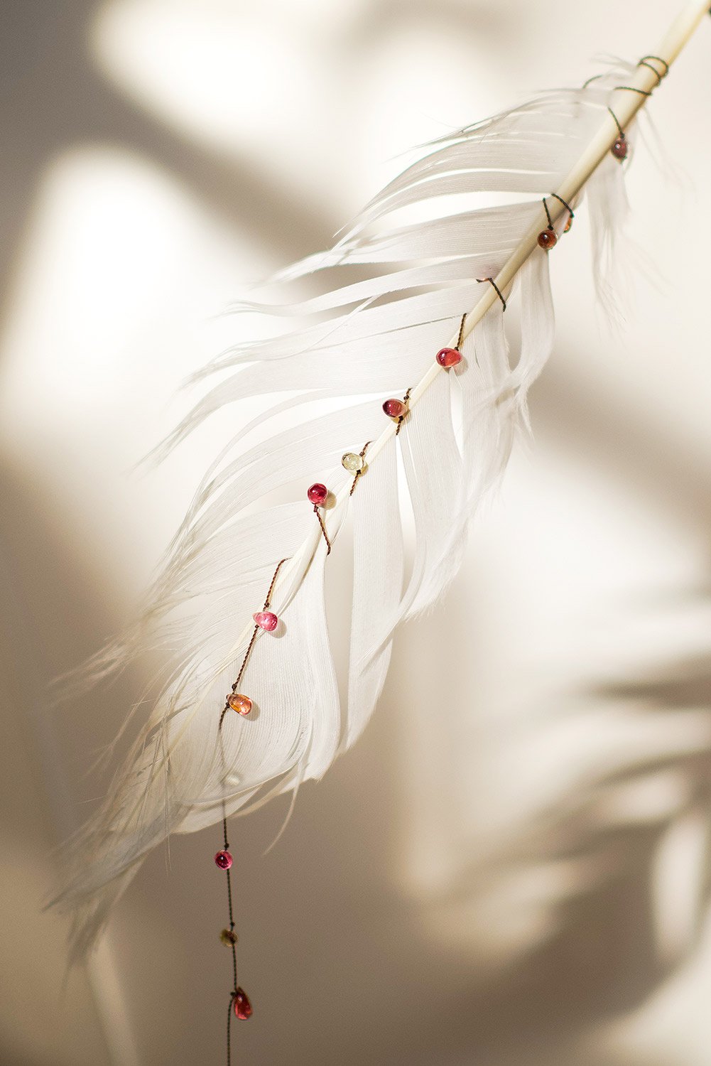 artfull display of tourmaline necklace with white feather, product photo shoot
