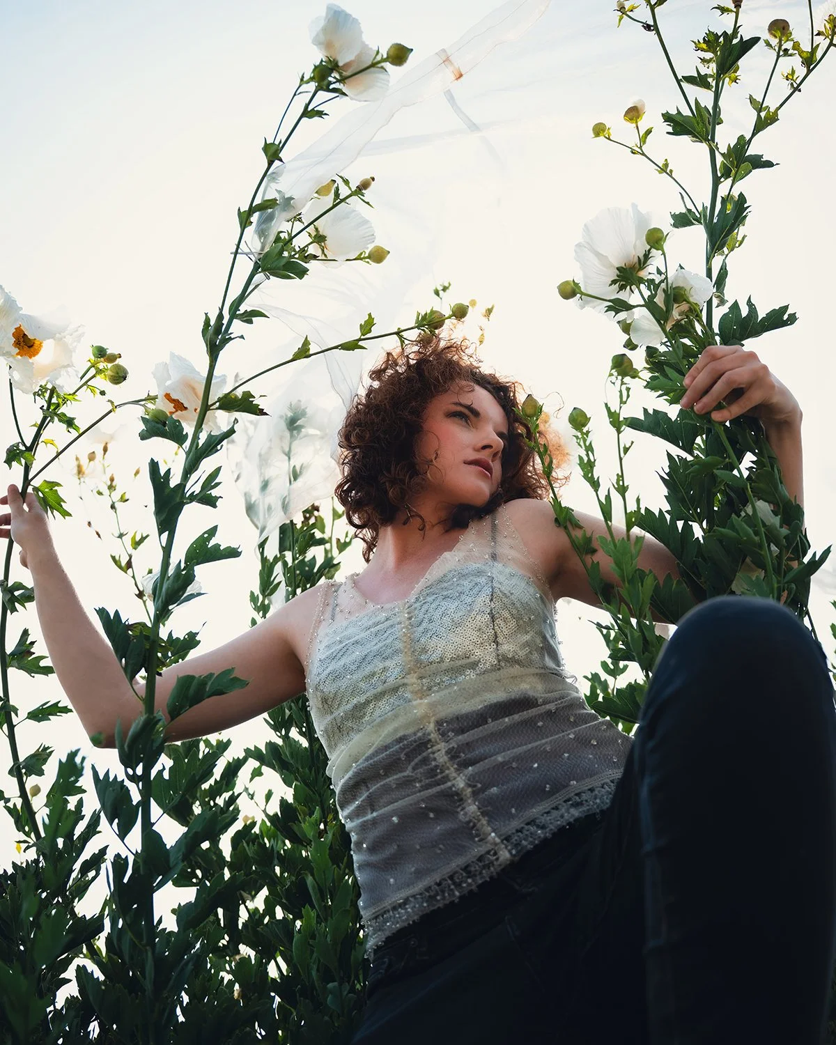 a woman gazes out from a stock of wild Matilija poppies in fashion editorial