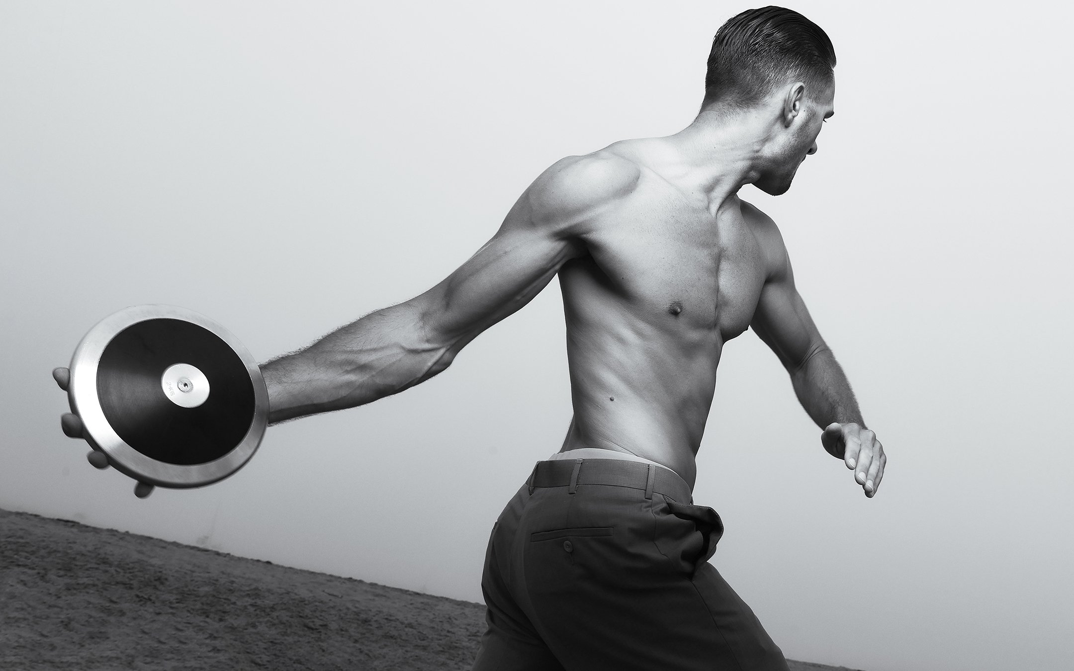 male model wearing slacks on beach in black and white image