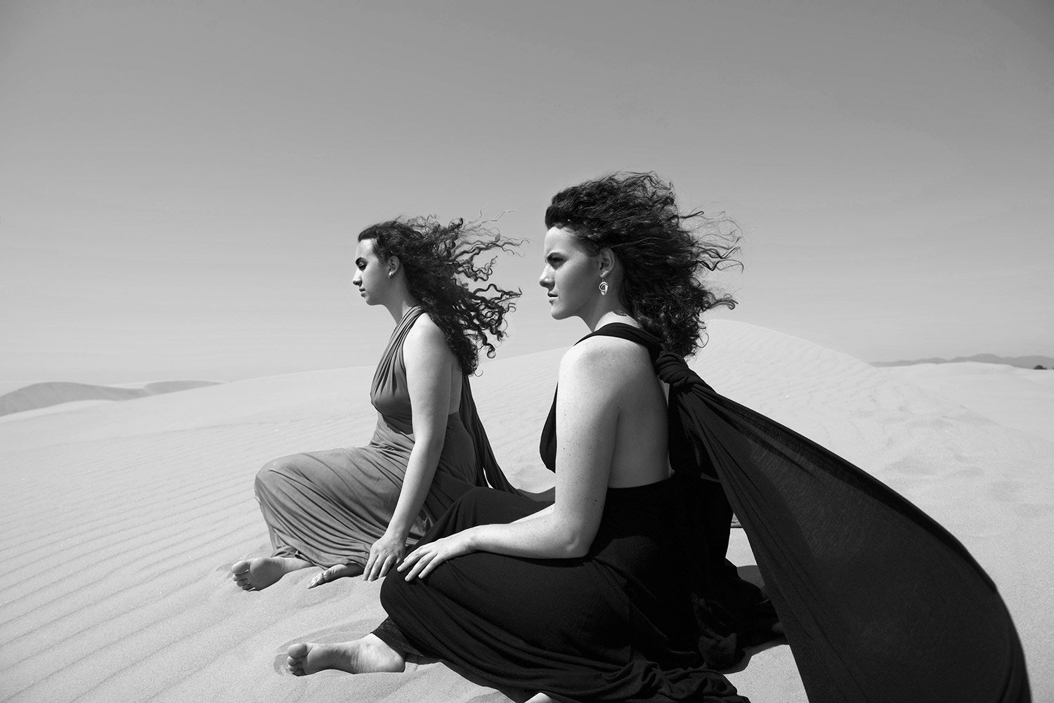 sisters in contemplative moment in sand dunes, portrait