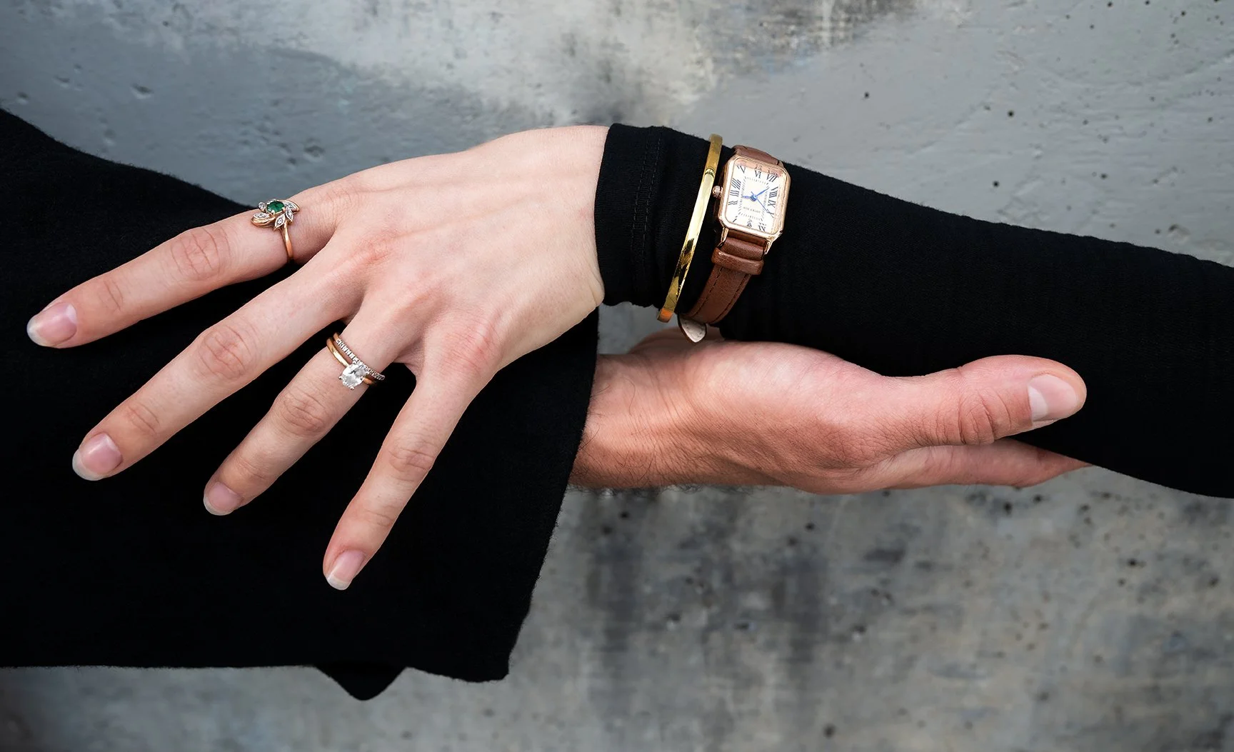 male and female hands touching hands with the focus on her jewelry