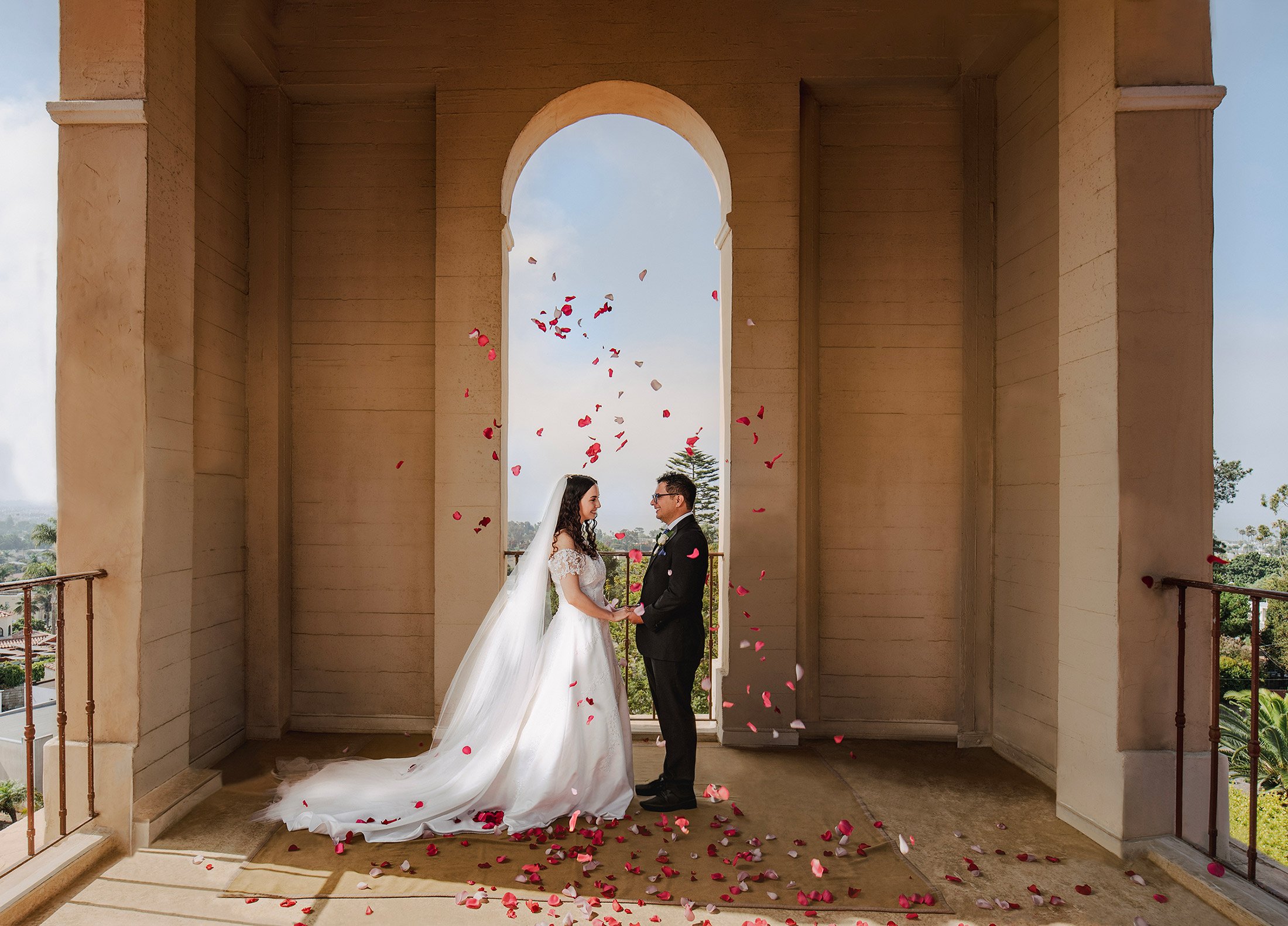 Rose petals fly around a newly wed bride and groom in a bell tower, Ventura