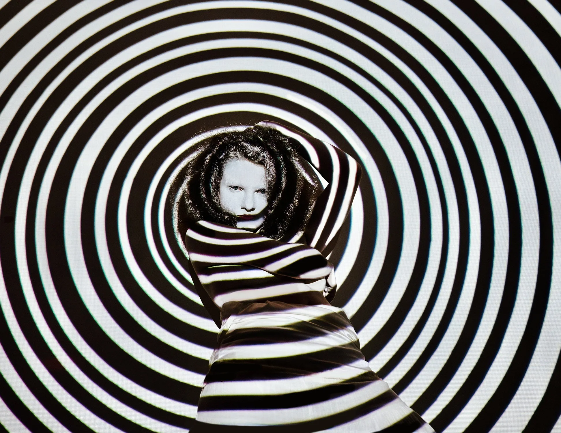 a woman stares intently through a spiral, creative