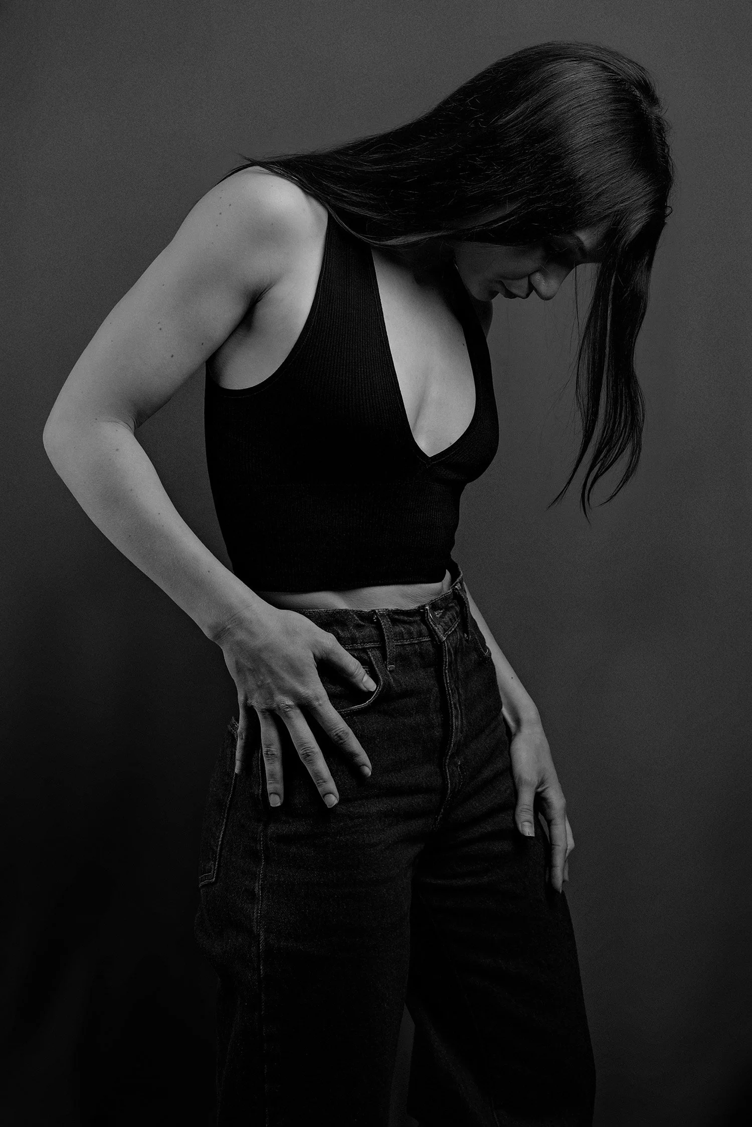 with hands on her designer jeans, model looks down