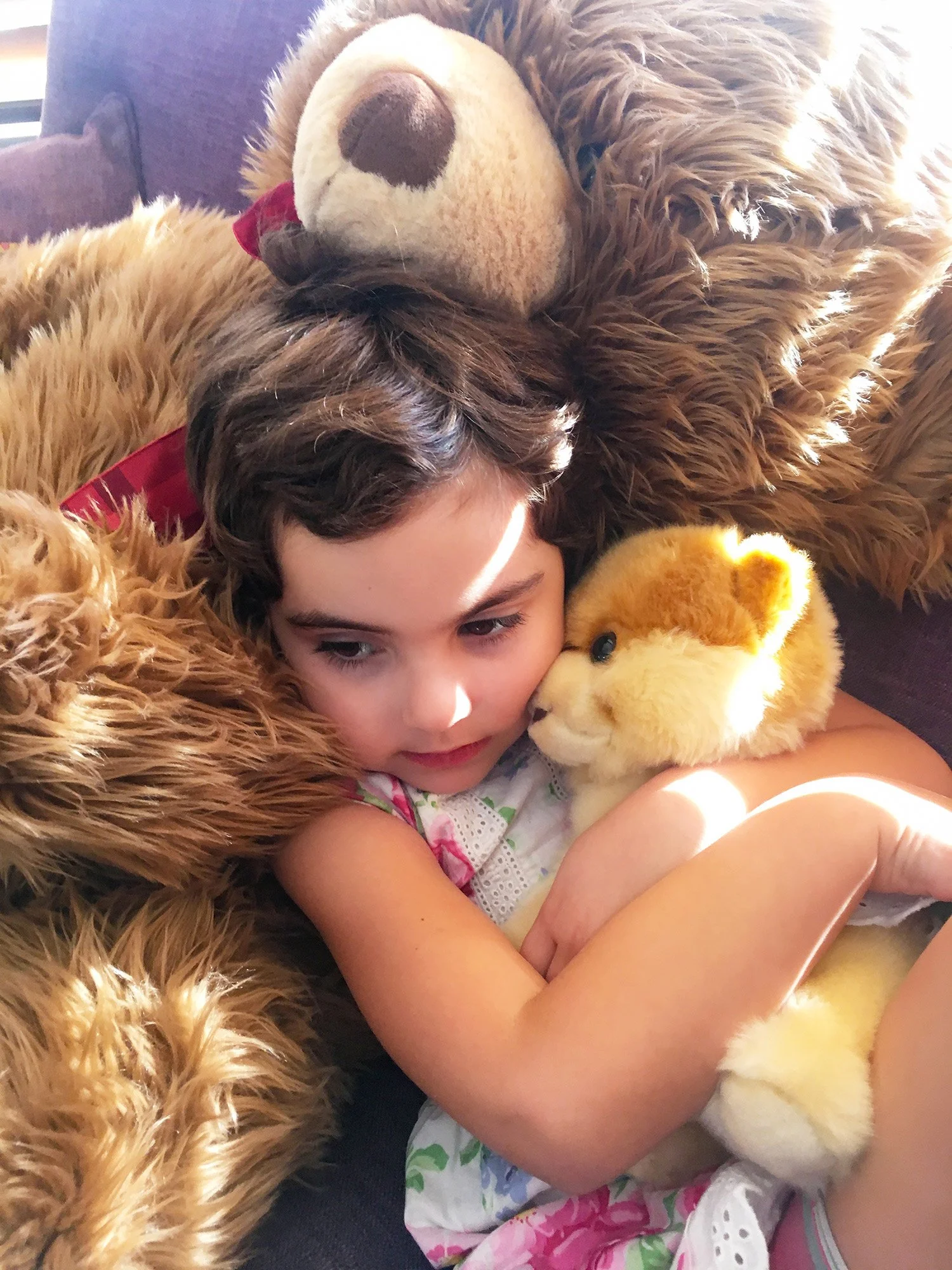 a young girl seeks some quiet time on her big teddy bear while holding her lion