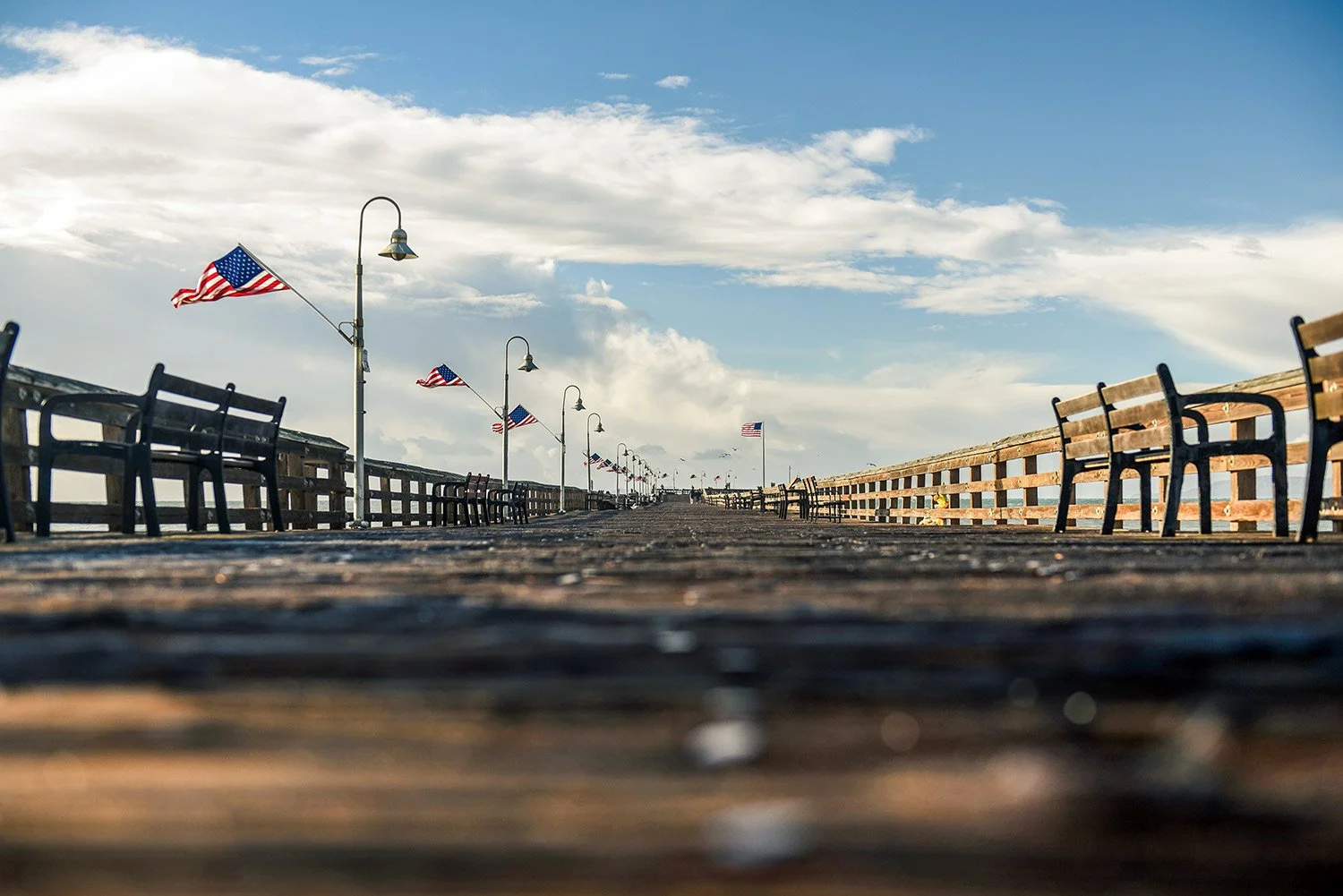 Linear photos of a Ventura pier at foot level with American flags line the pier