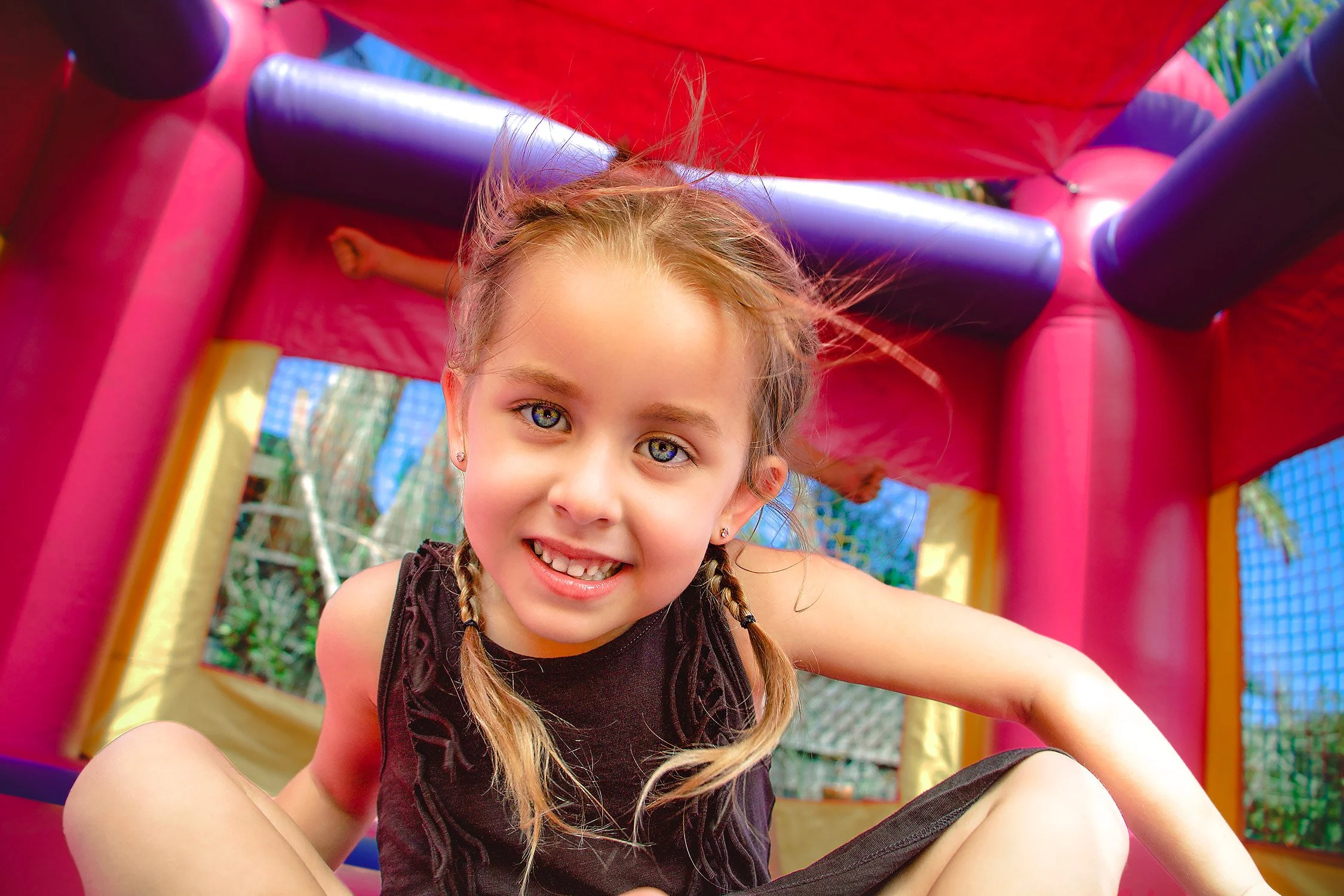 Young girl smiles from inside the bouncy house at a birthday party, Ojai