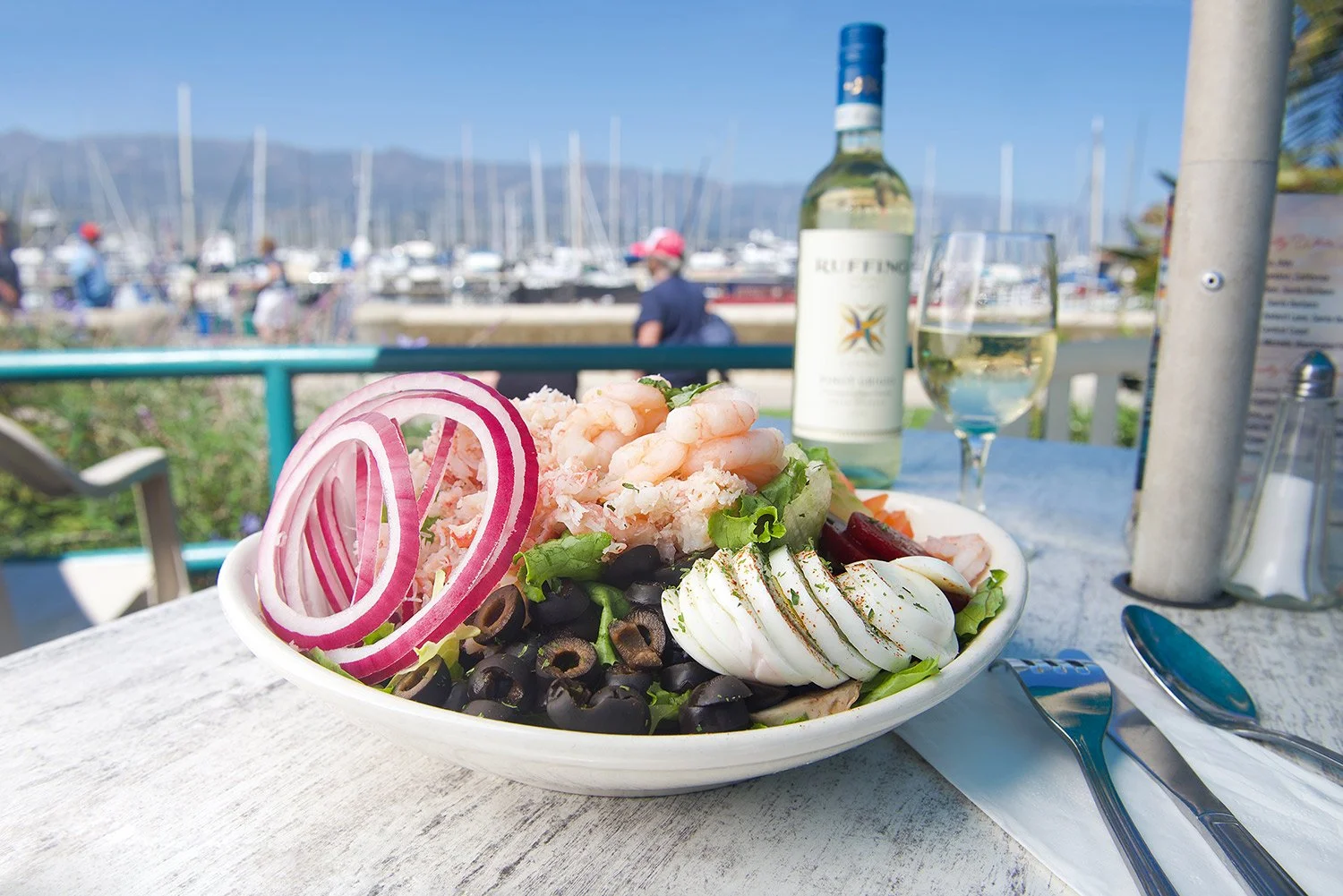 a fresh salad sits on a table at a harbor restaurant