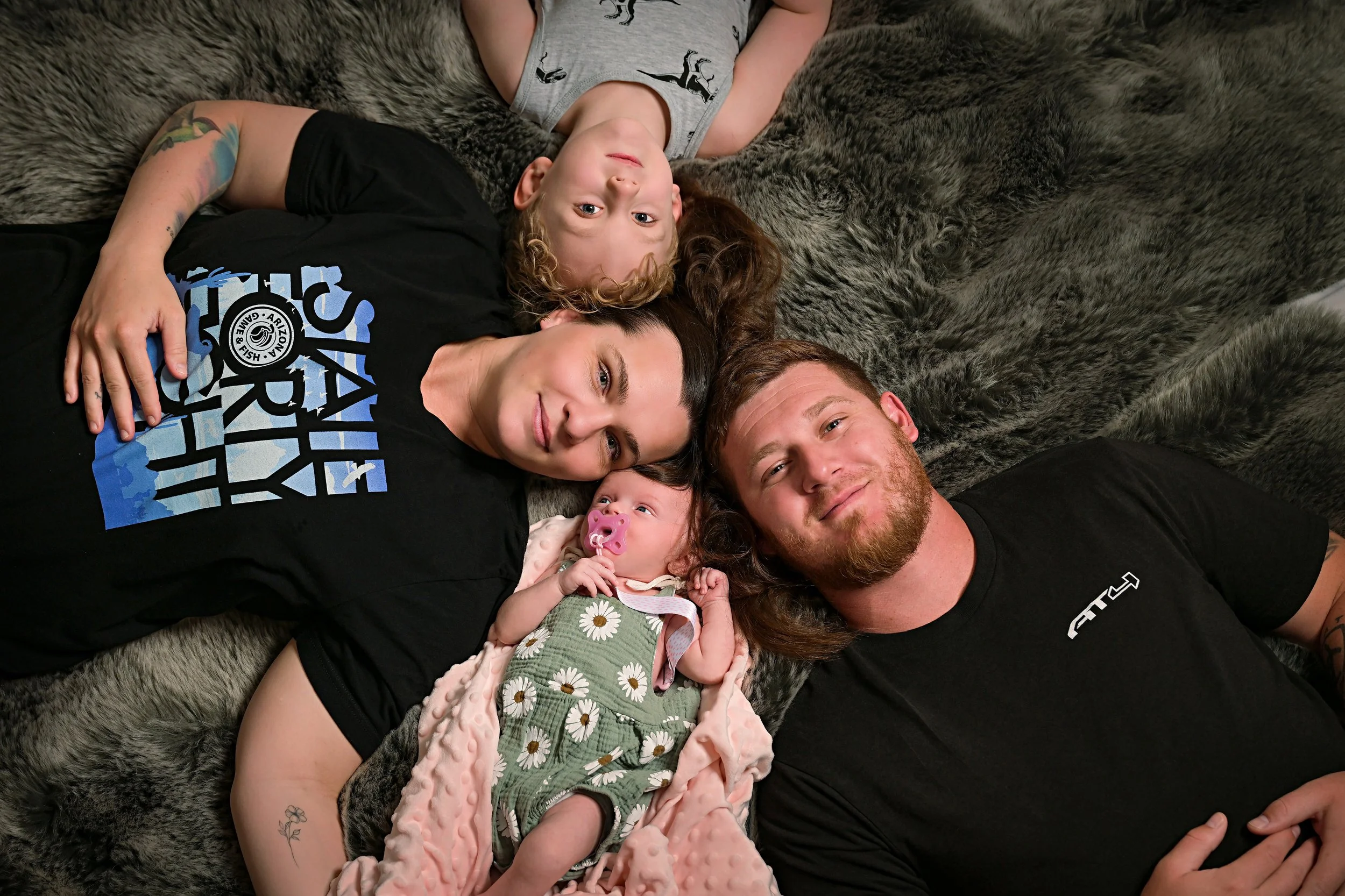 A young family lying on a bed looks up for a family portrait