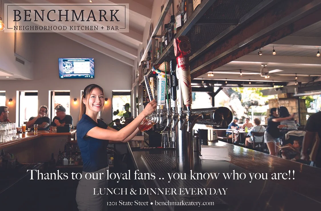 Female bartender smiling and pouring beer at Benchmark Eatery Santa Barbara