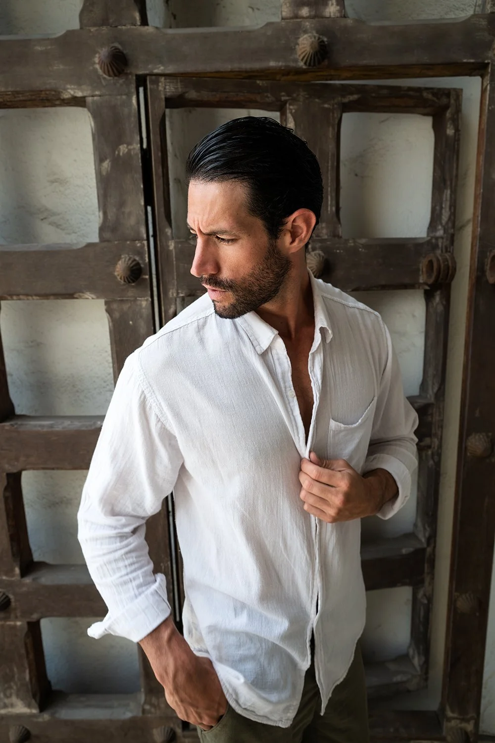 Close-up of a men's white linen button-down shirt styled on a Spanish male model in an editorial menswear fashion shoot.