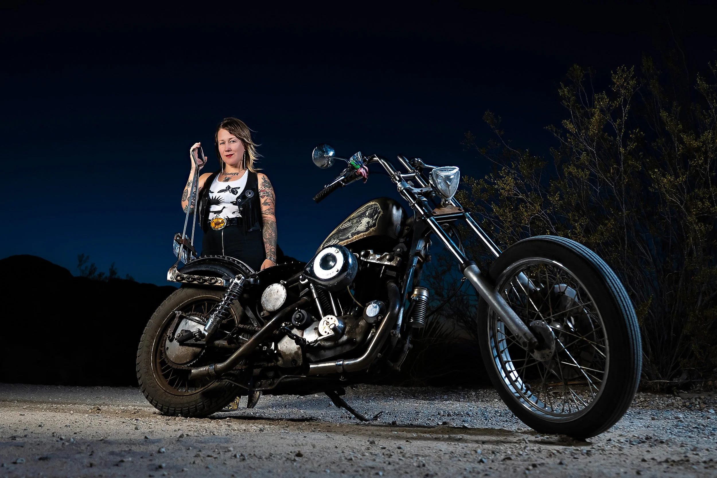 Cinematic motorcycle photography of a bike leaning into a curve and a member of Ride to the Warehouse behind the bike