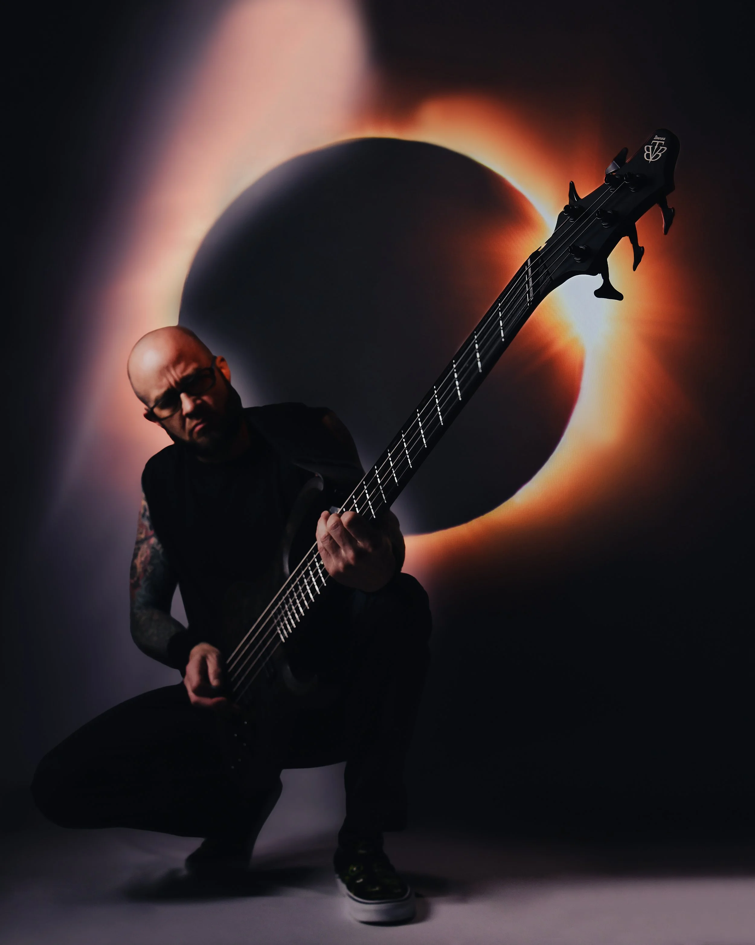 man playing guitar with eclipse on the screen behind him