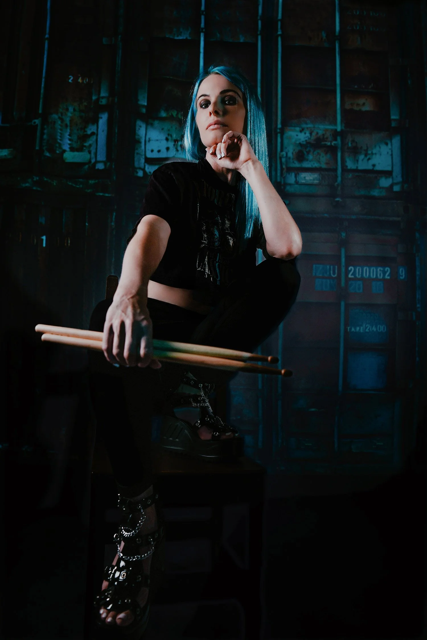 female drummer from local heavy metal band holds drum sticks for a moody portrait