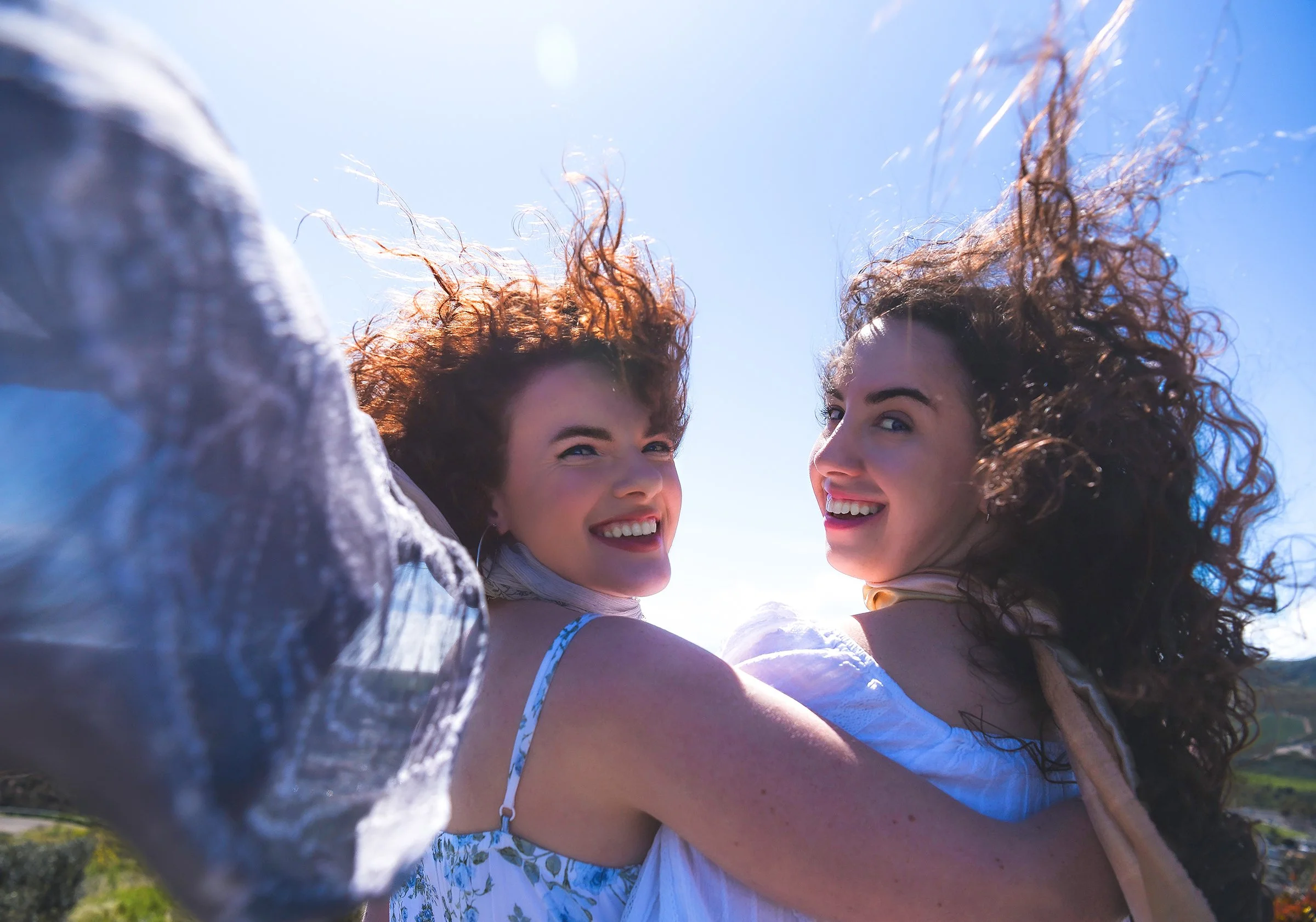 sisters smiling in the wind with blowing scarves