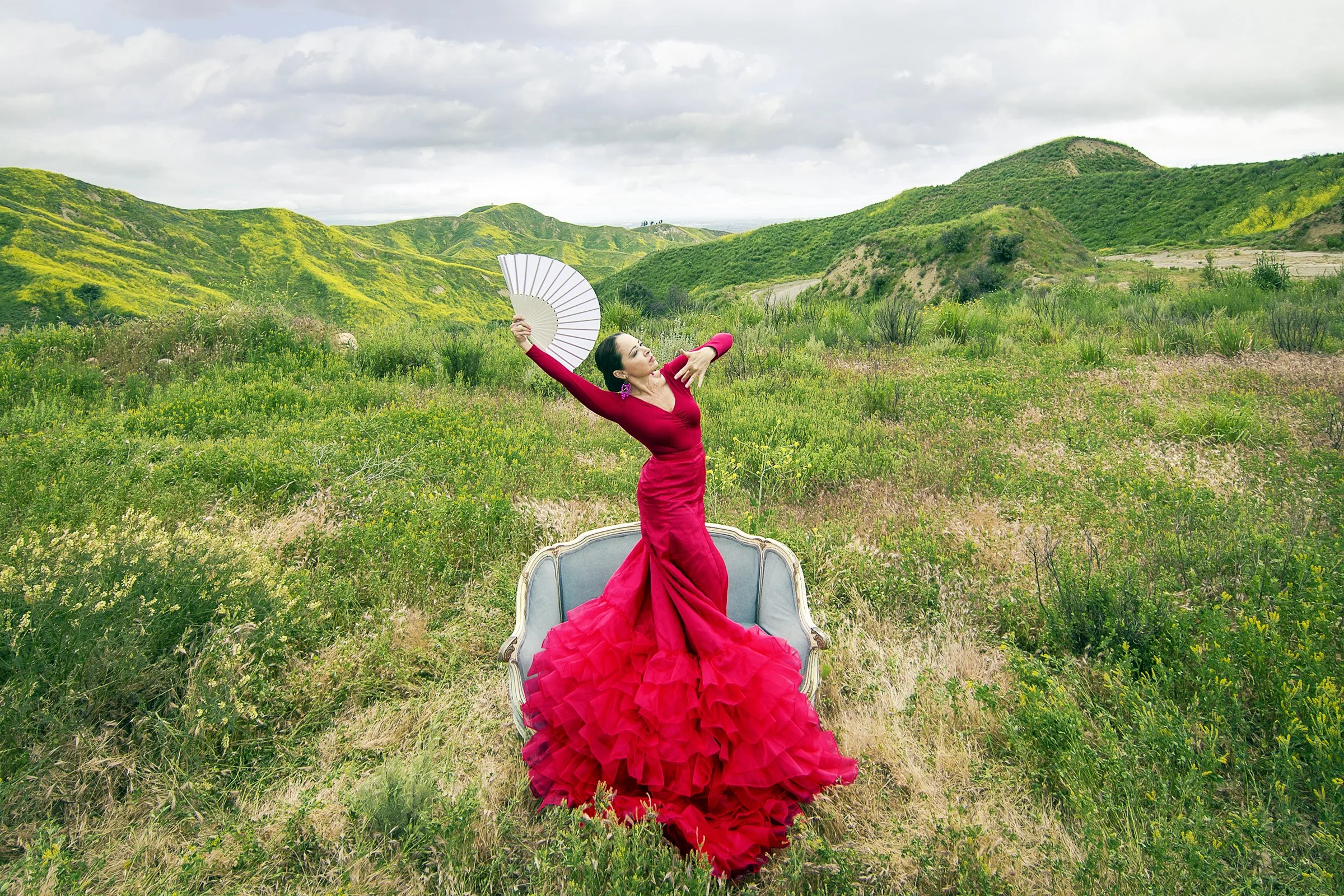 Photograph of a flamenco dancer in a vibrant red dress in the rolling hills of Ventura California