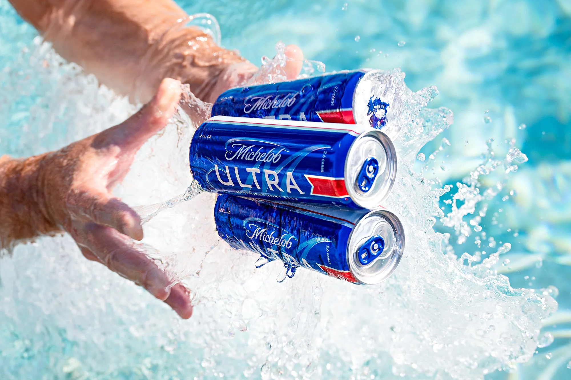 Summer ad campaign with natural lighting of beer being tossed in a pool.
