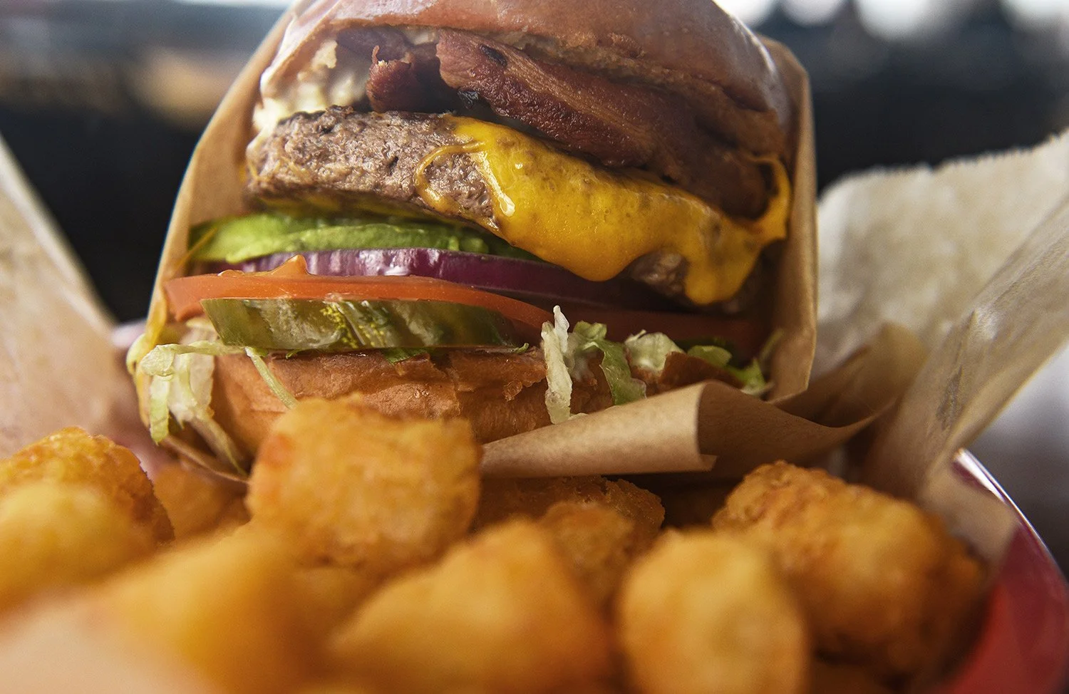 close up of a double beef patty burger and tater tots