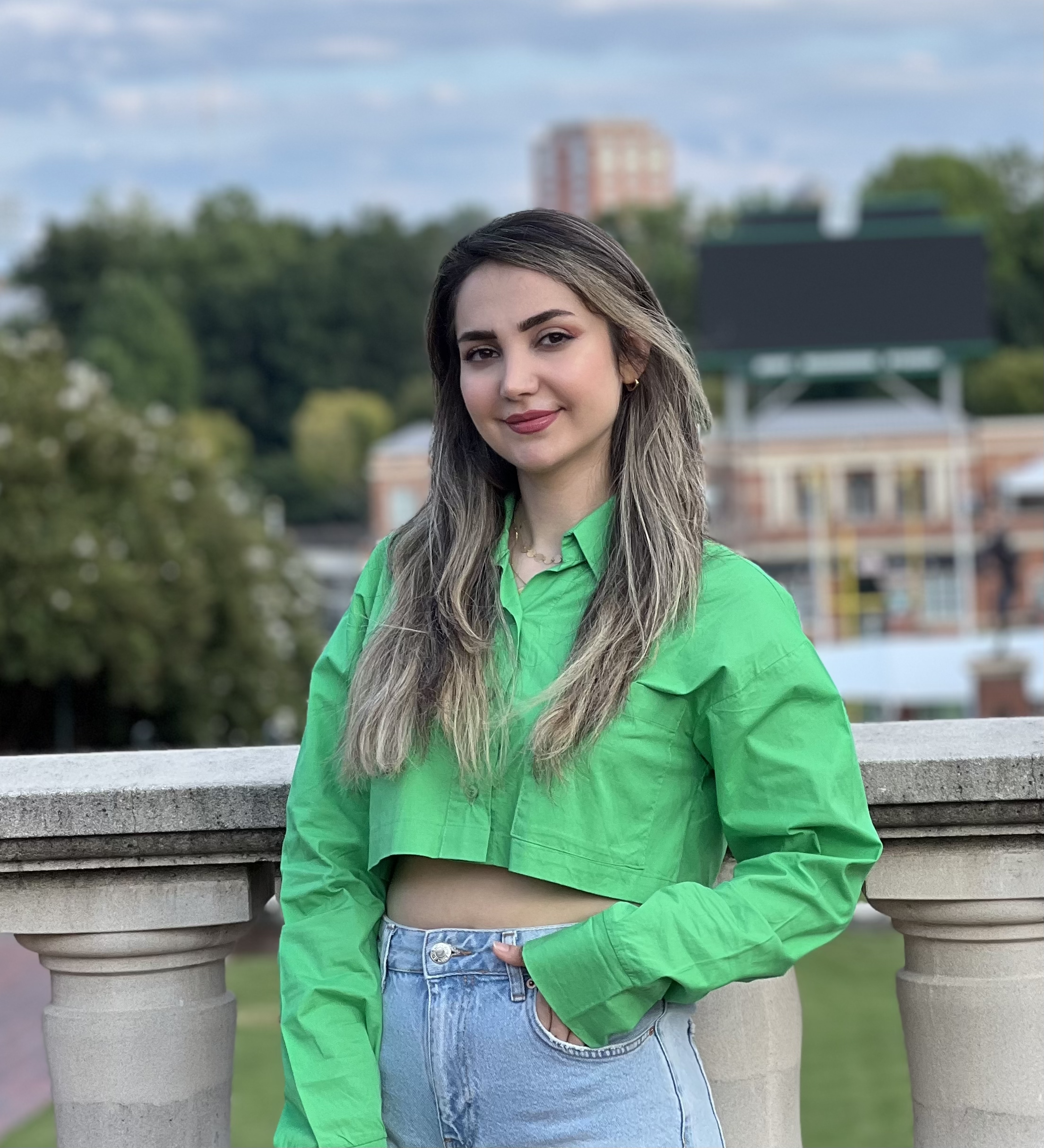Pegah wears a neon green jacket. She has brown hair with blonde highlights