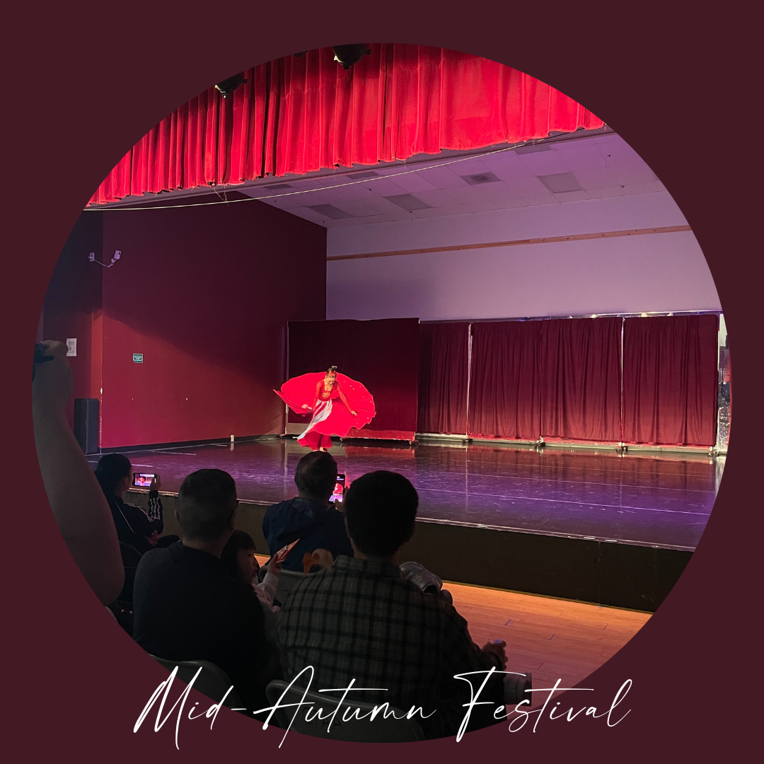 A dancer in a red dress performing on stage during Mid-Autumn Festival, with an audience watching and recording the performance.