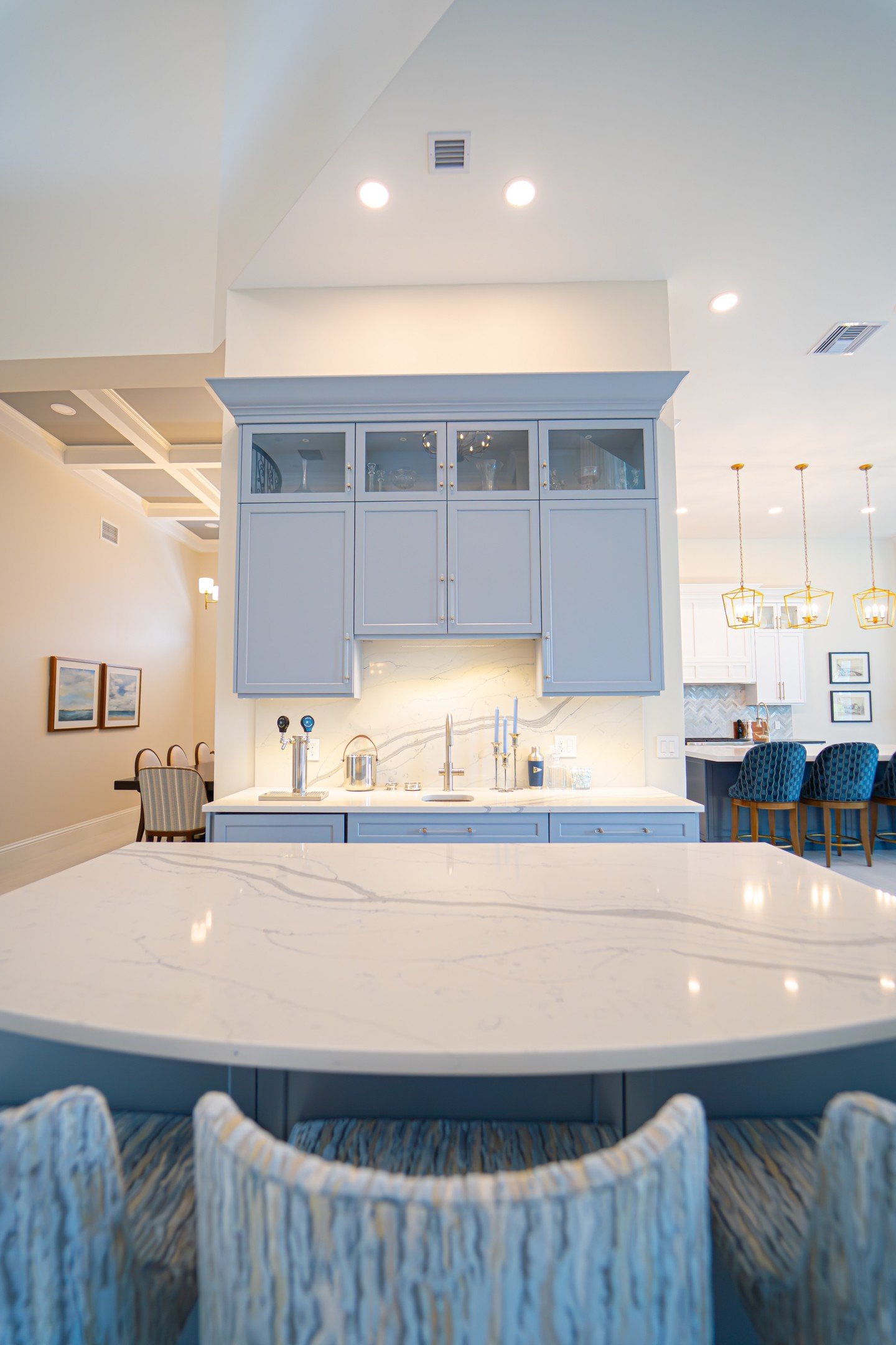 This wet bar is the perfect blend of form and function soft blue cabinetry, elegant marble countertops, and subtle lighting create a gorgeous focal point. The glass-front upper cabinets add a touch of sophistication while keeping favorite glassware o