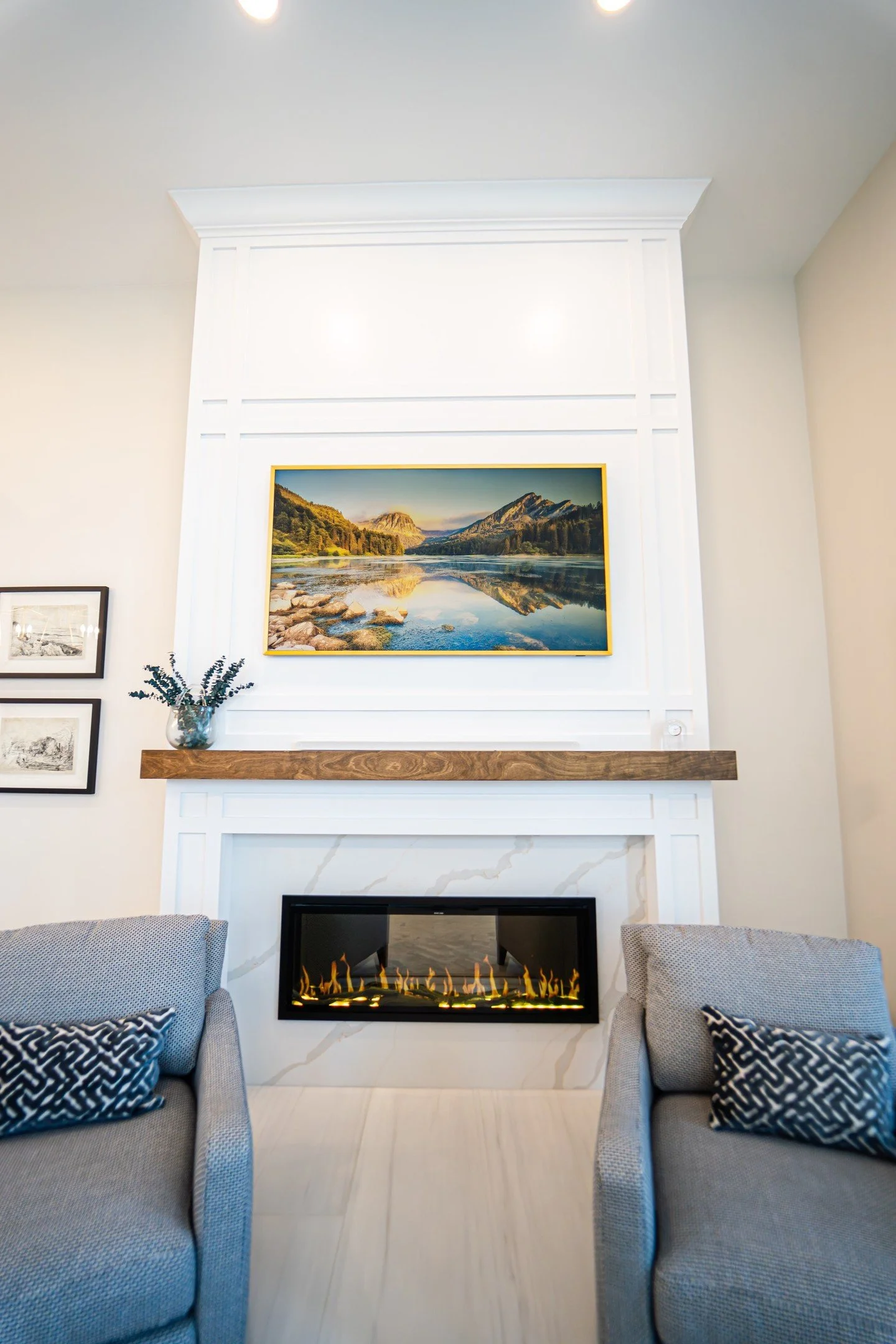 This sleek fireplace brings warmth and style to the space, framed with elegant white millwork and a natural wood mantle that adds a touch of rustic charm. The linear flame display delivers a modern, cozy vibe, perfect for relaxing nights in. Topped w